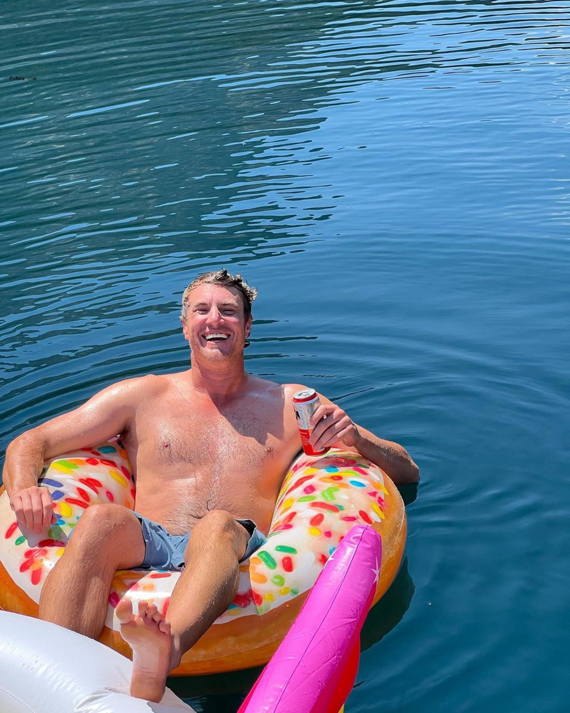 Shep Rose sitting shirtless on a floatie.