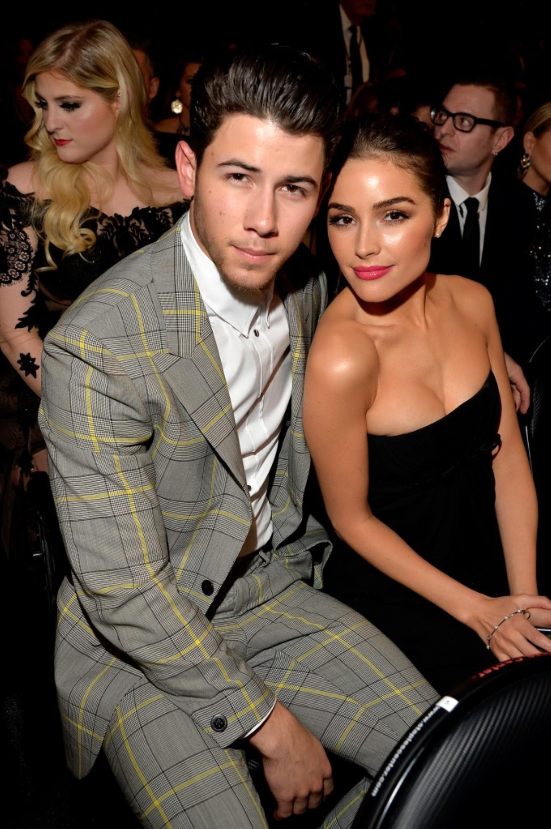 Nick Jo<i></i>nas and Olivia Culpo sitting together at an awards show.