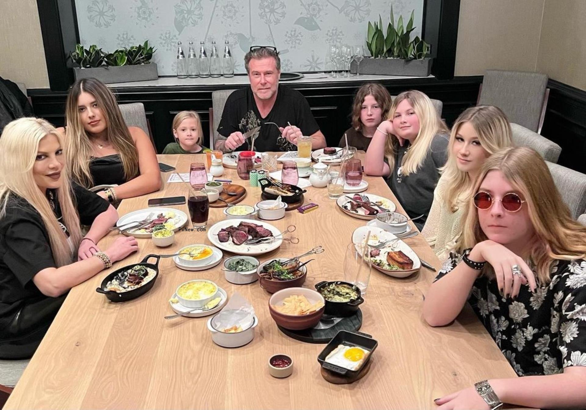 Tori Spelling and Dean McDermott sitting down at a table with their kids.