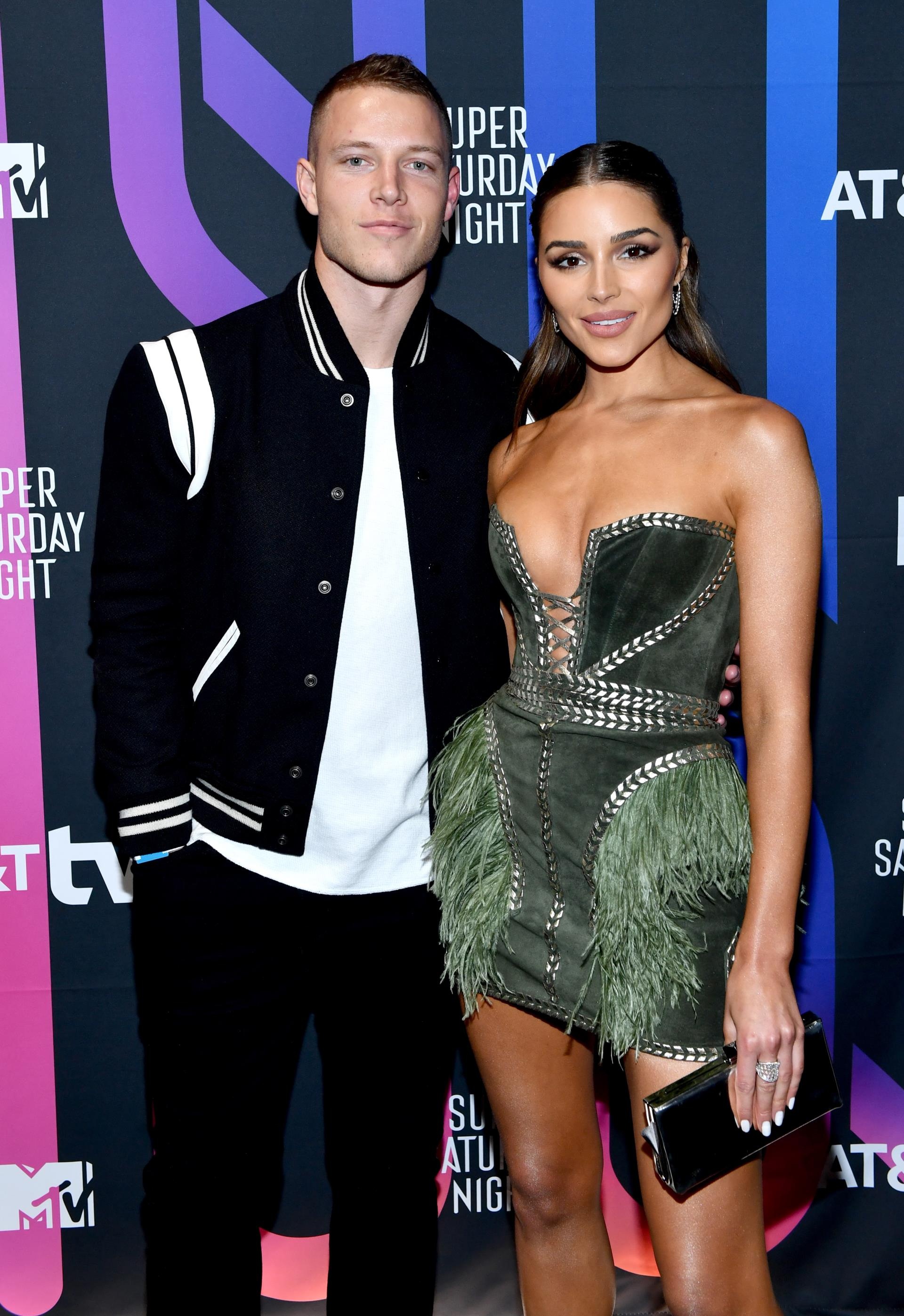 Olivia Culpo and Christian McCaffrey posing on a red carpet together.