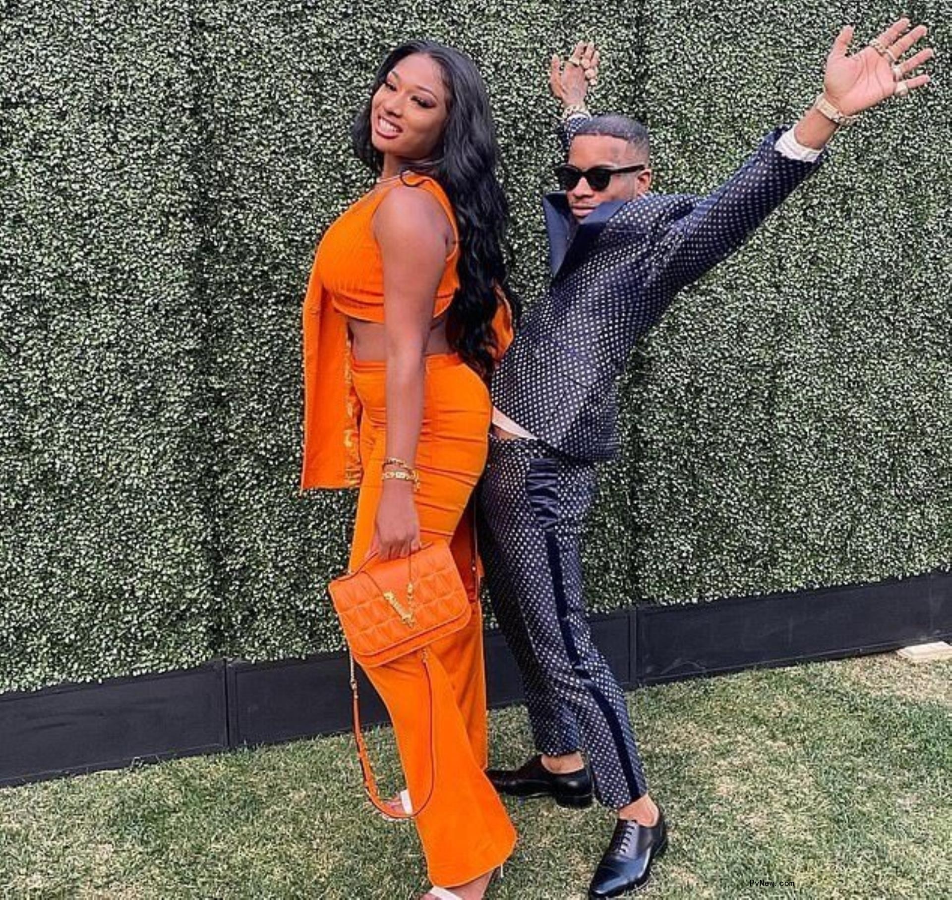 Tory Lanez in black posing behind Megan Thee Stallion in orange.