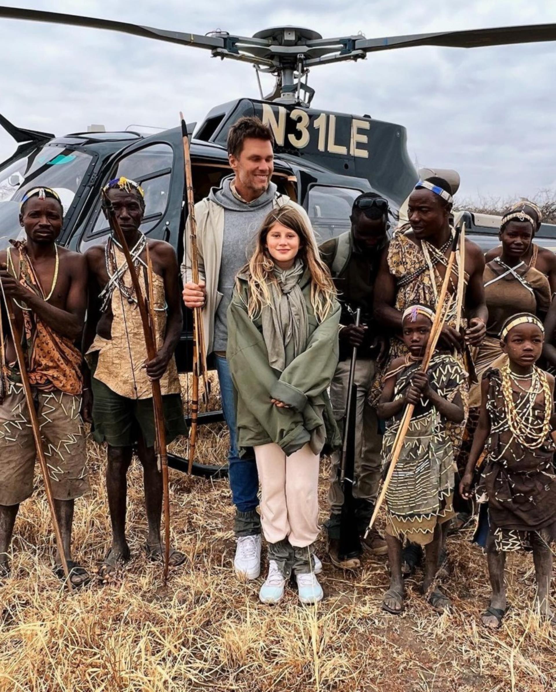 tom brady and his daughter standing in front of a helicopter with a tribes of people