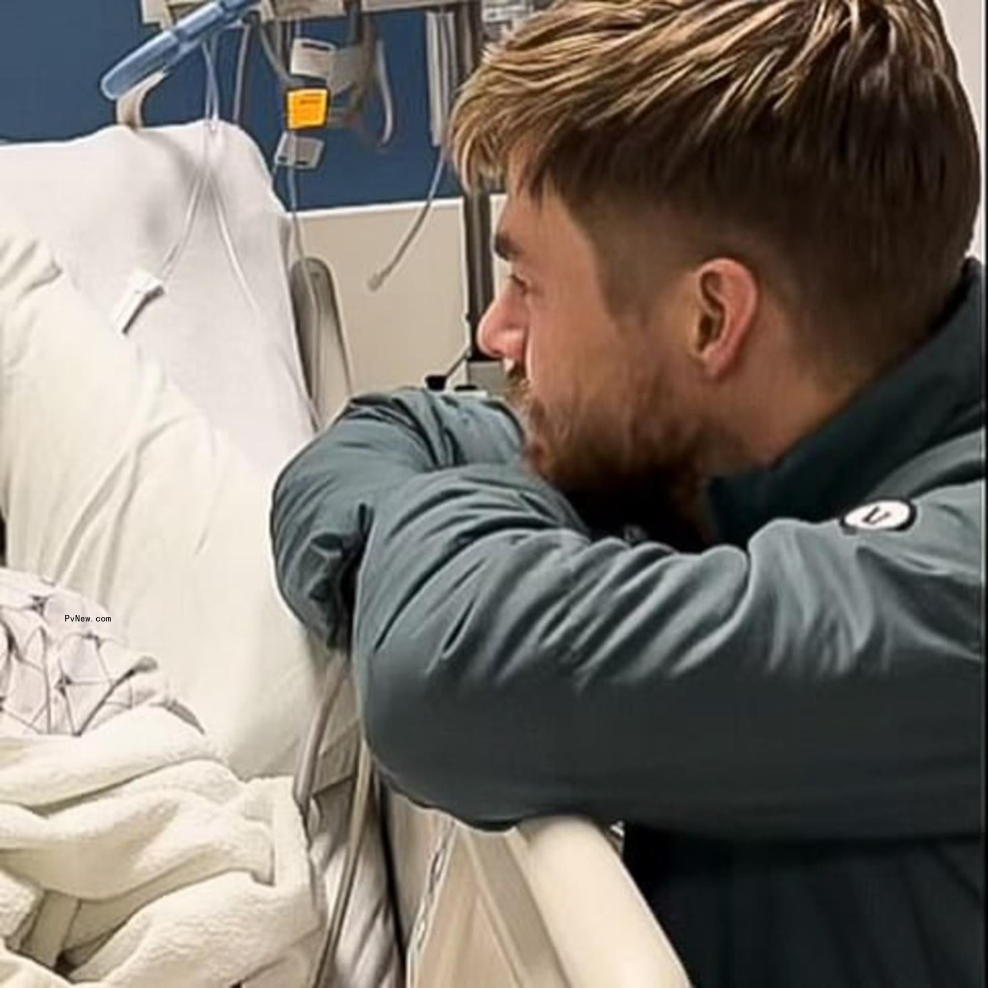 Derek Hough sitting by Hayley Erbert's hospital bed.
