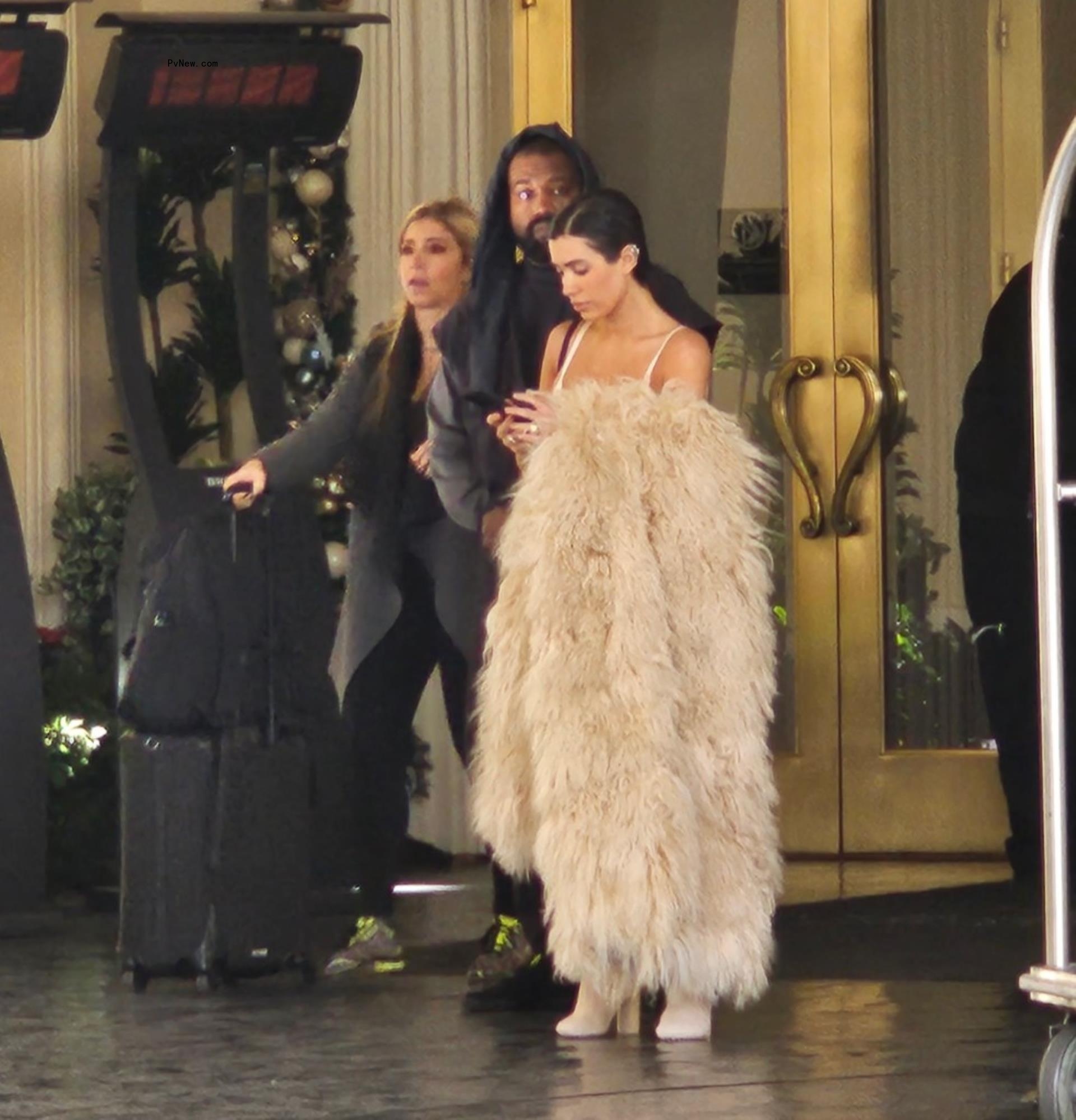Bianca Censori looking down at her phone next to Kanye West