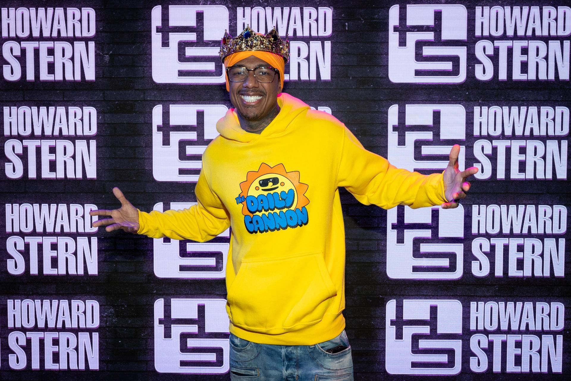 Nick Cannon poses in crown and yellow hoodie
