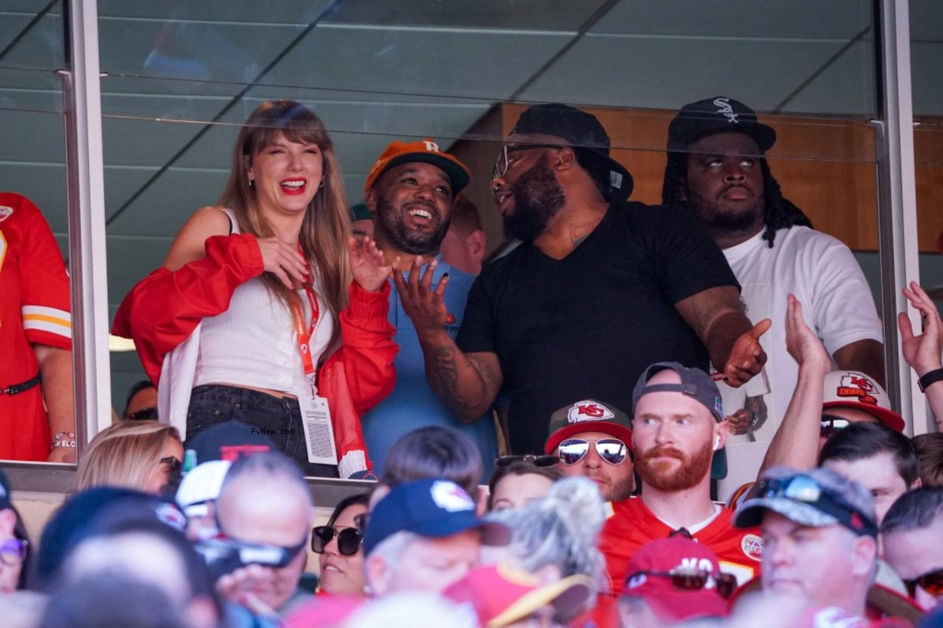 taylor swift sitting in the players box laughing with people