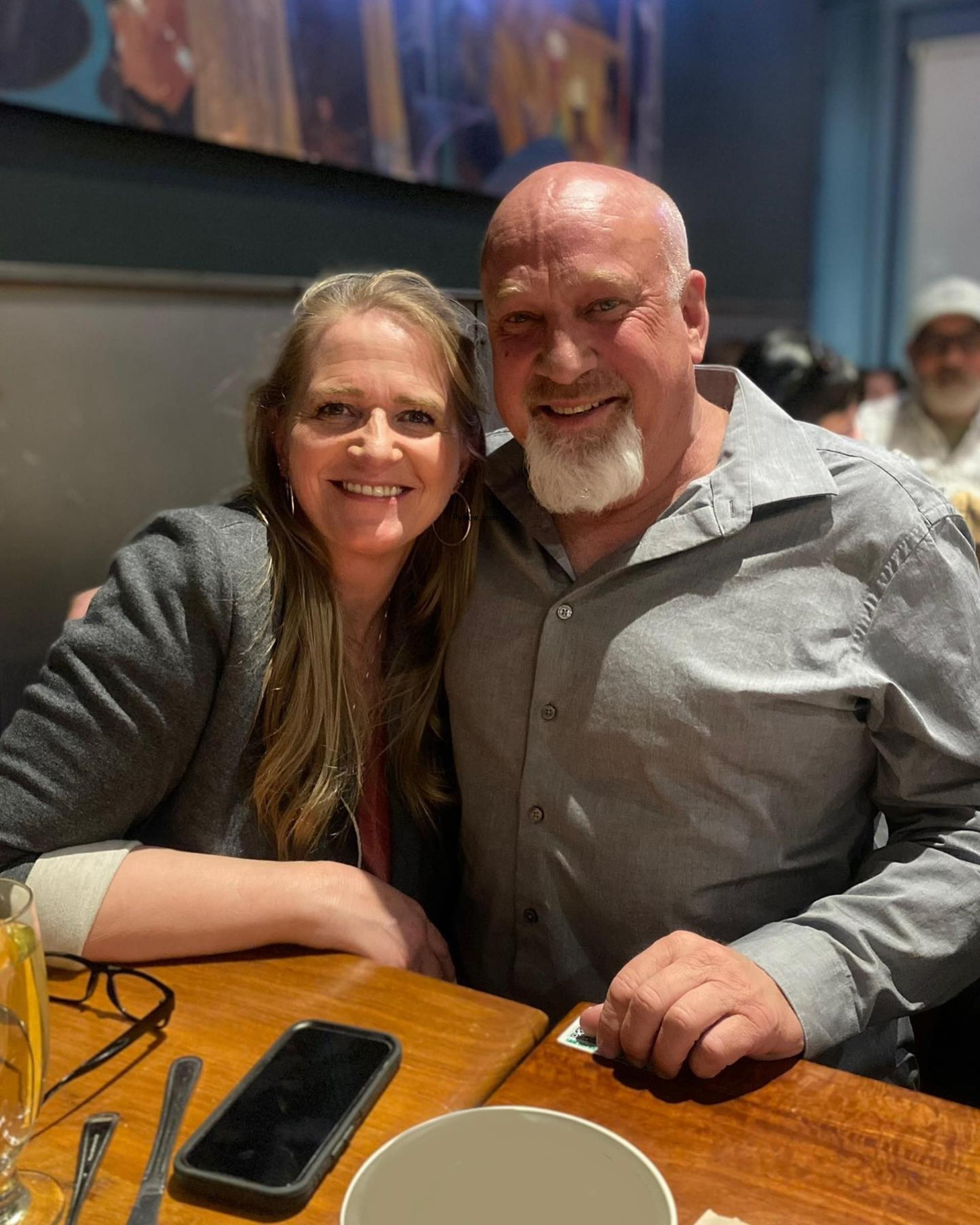Christine Brown and David Woolley smile while seated
