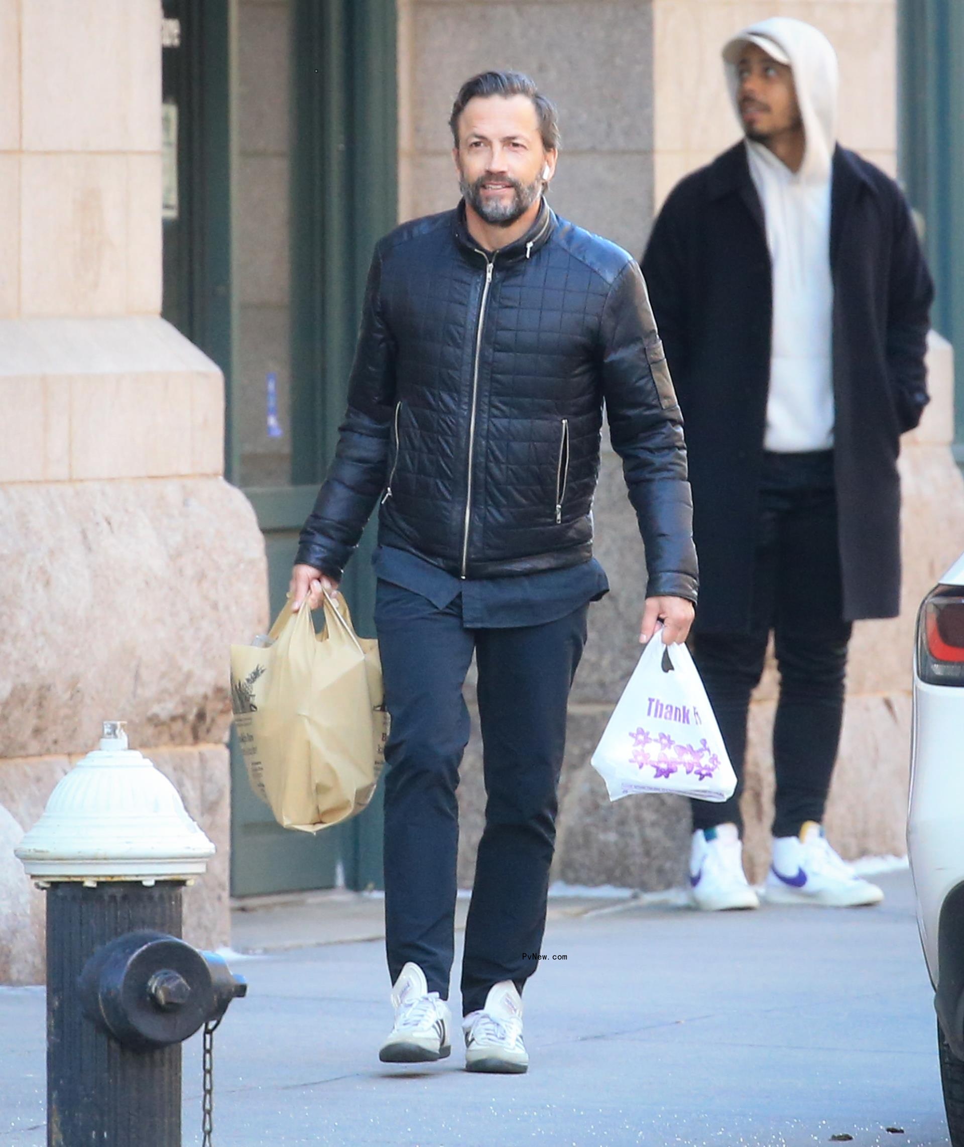 Andrew Shue walking holding grocery bags