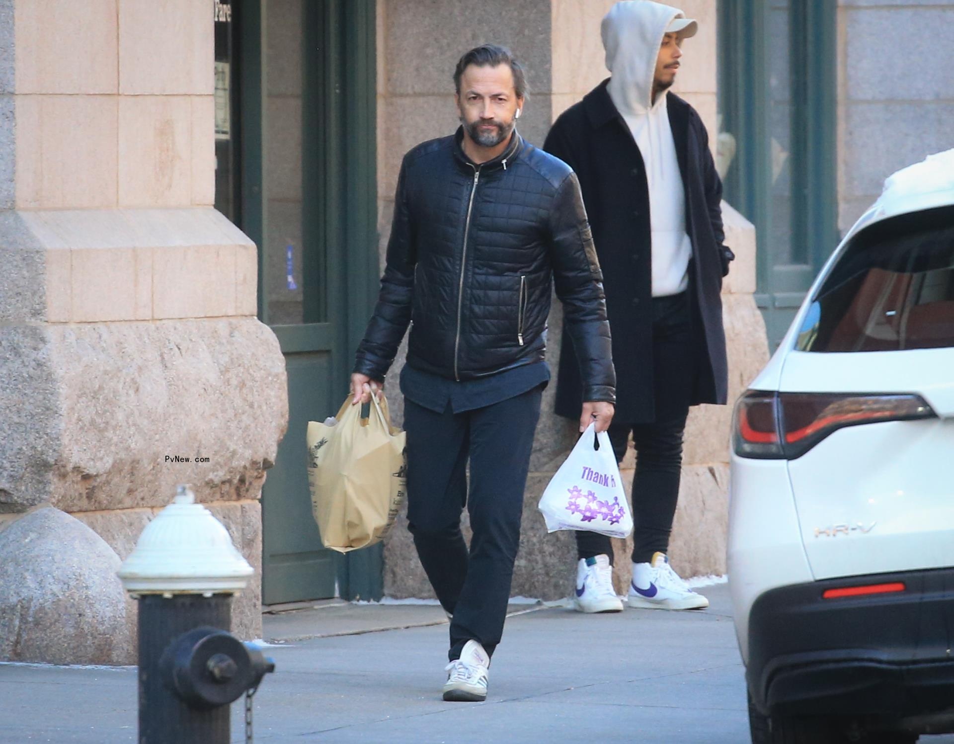 Andrew Shue walking holding grocery bags