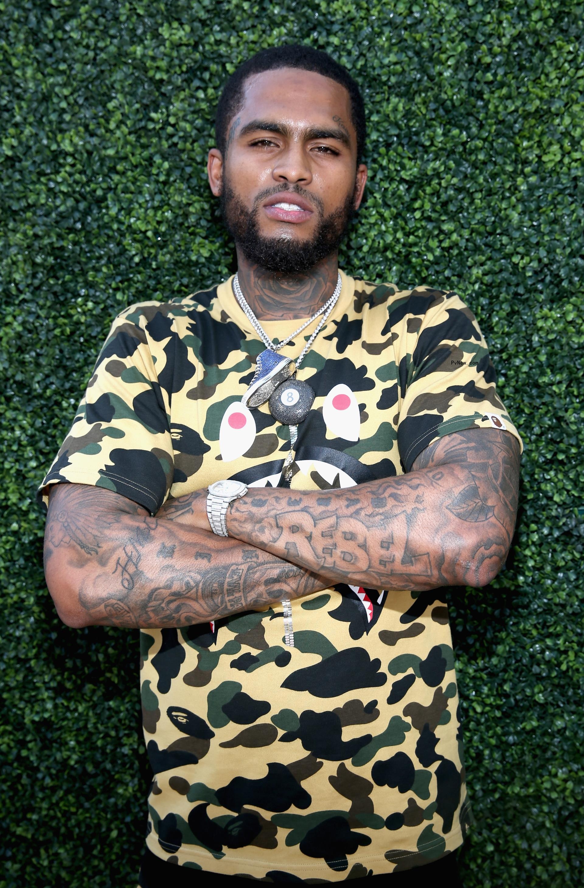 Dave East posing with arms crossed in yellow fatigue.