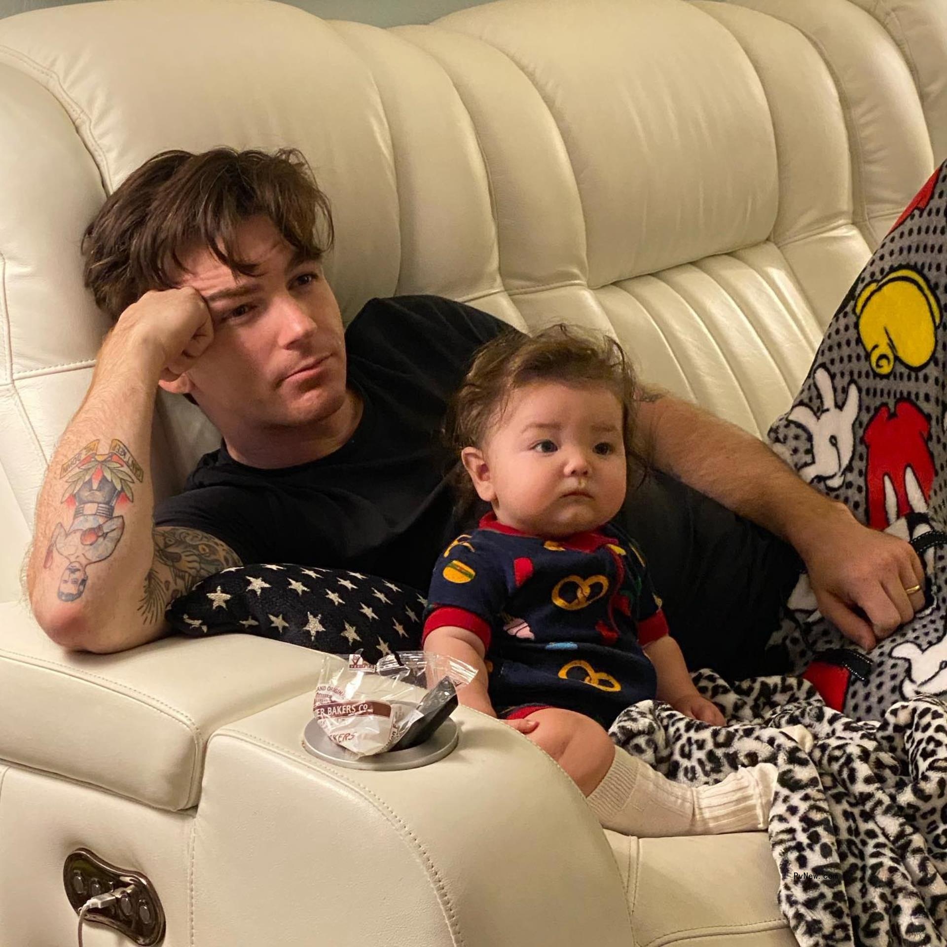 Drake Bell lying down on a couch with his son.