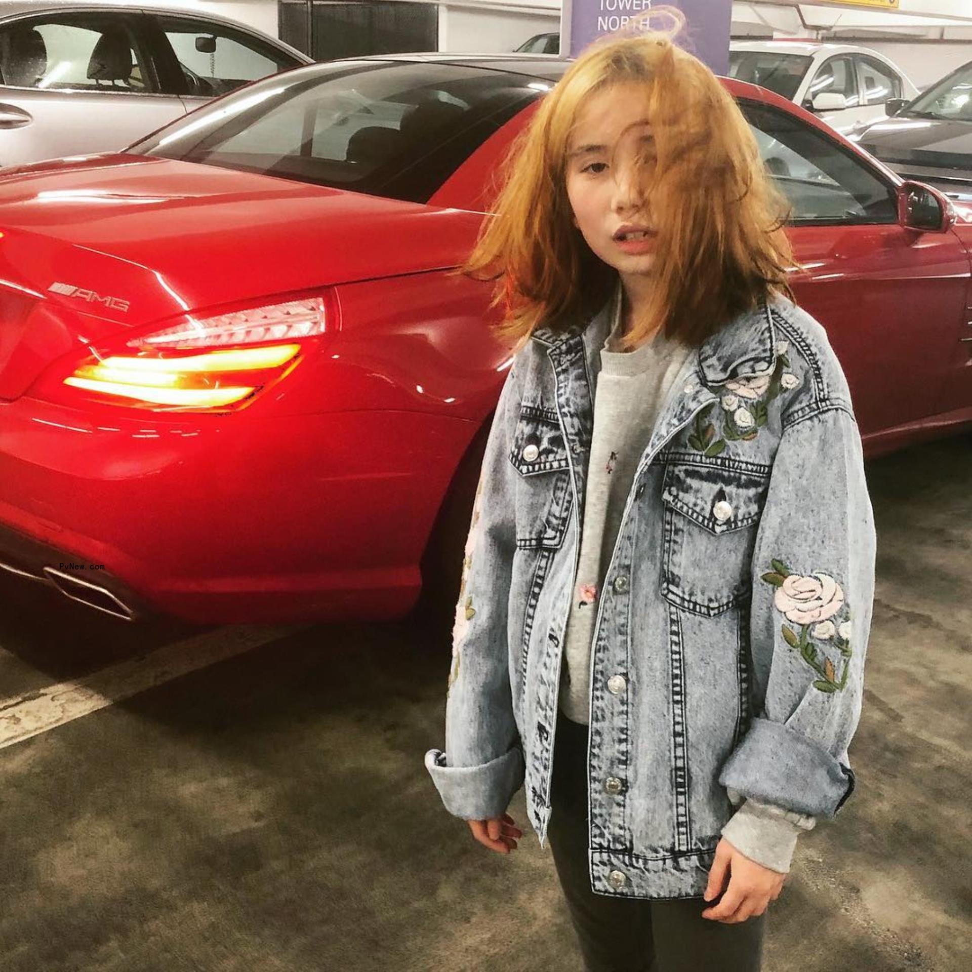 Lil Tay in front of a car.