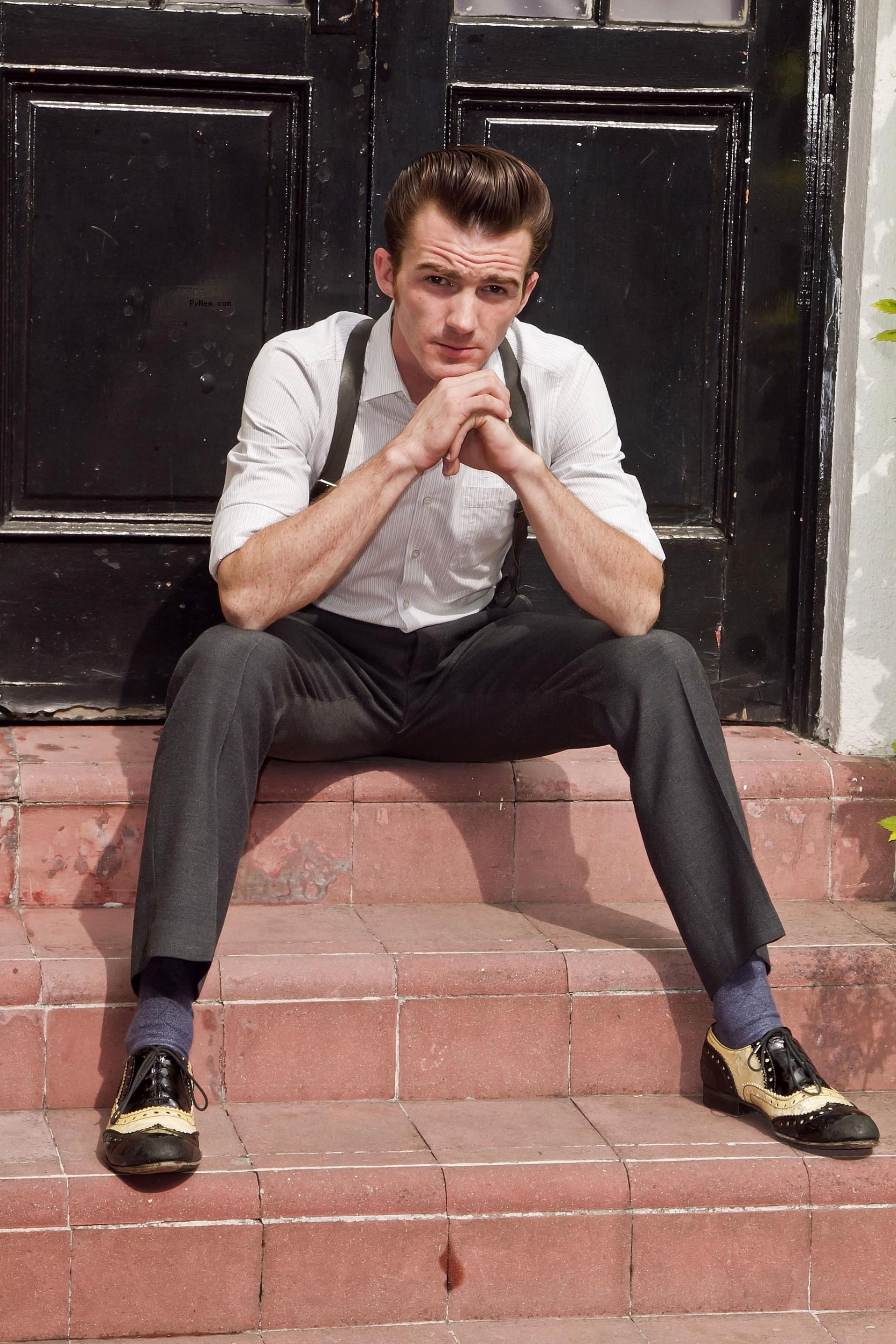 Drake Bell sitting on stairs.