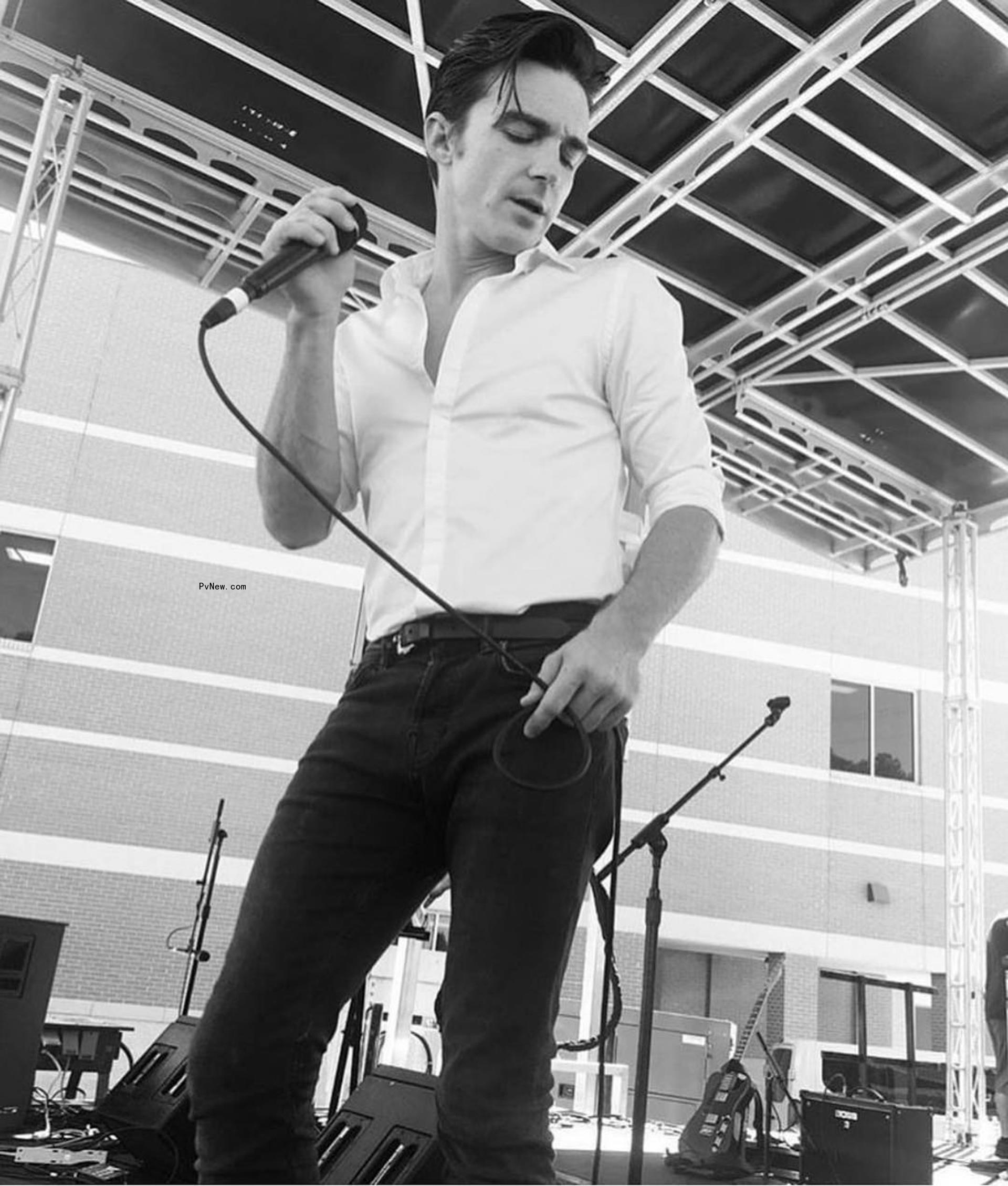 Drake Bell holding a mic and performing.