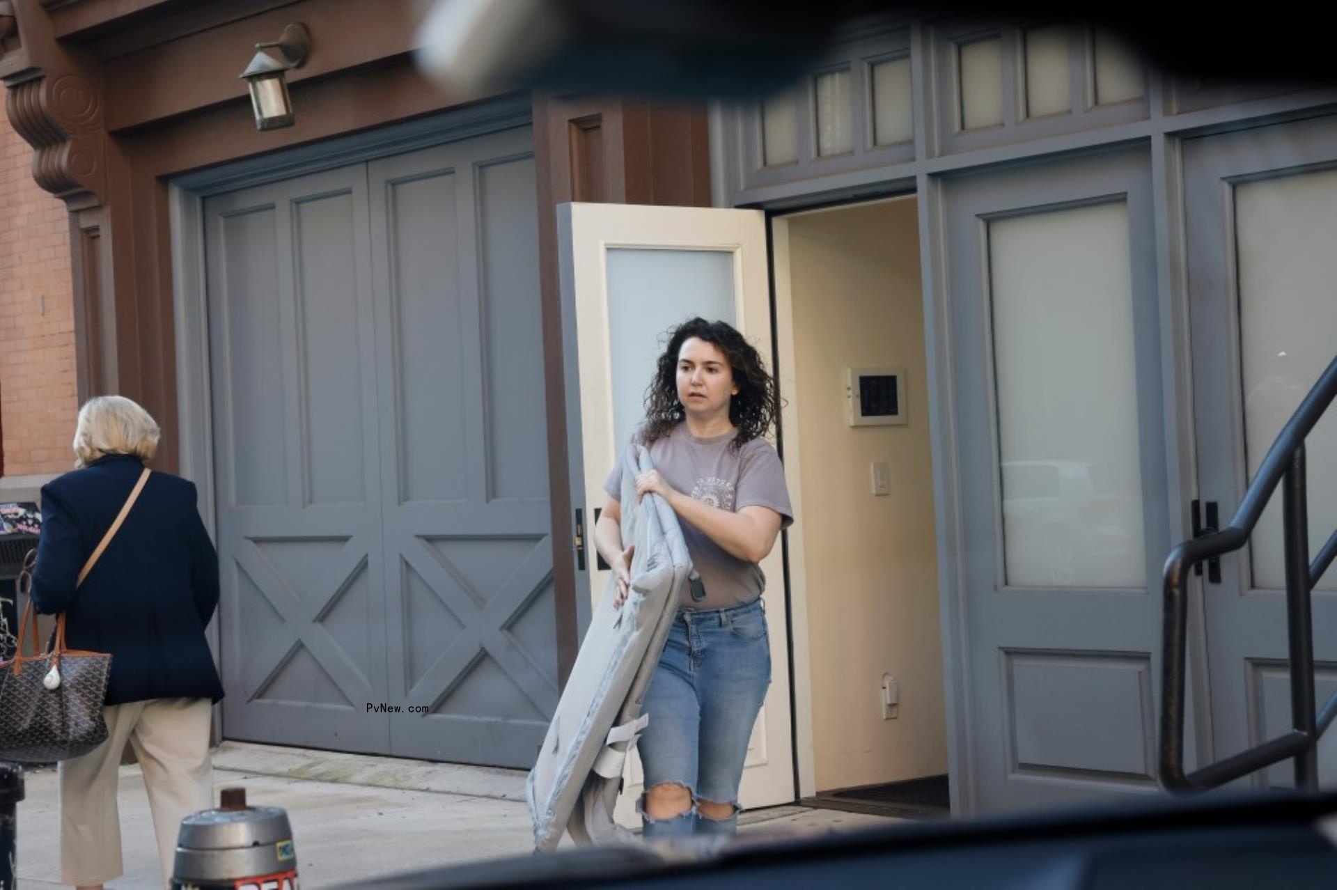 Woman carrying crib out of NYC building