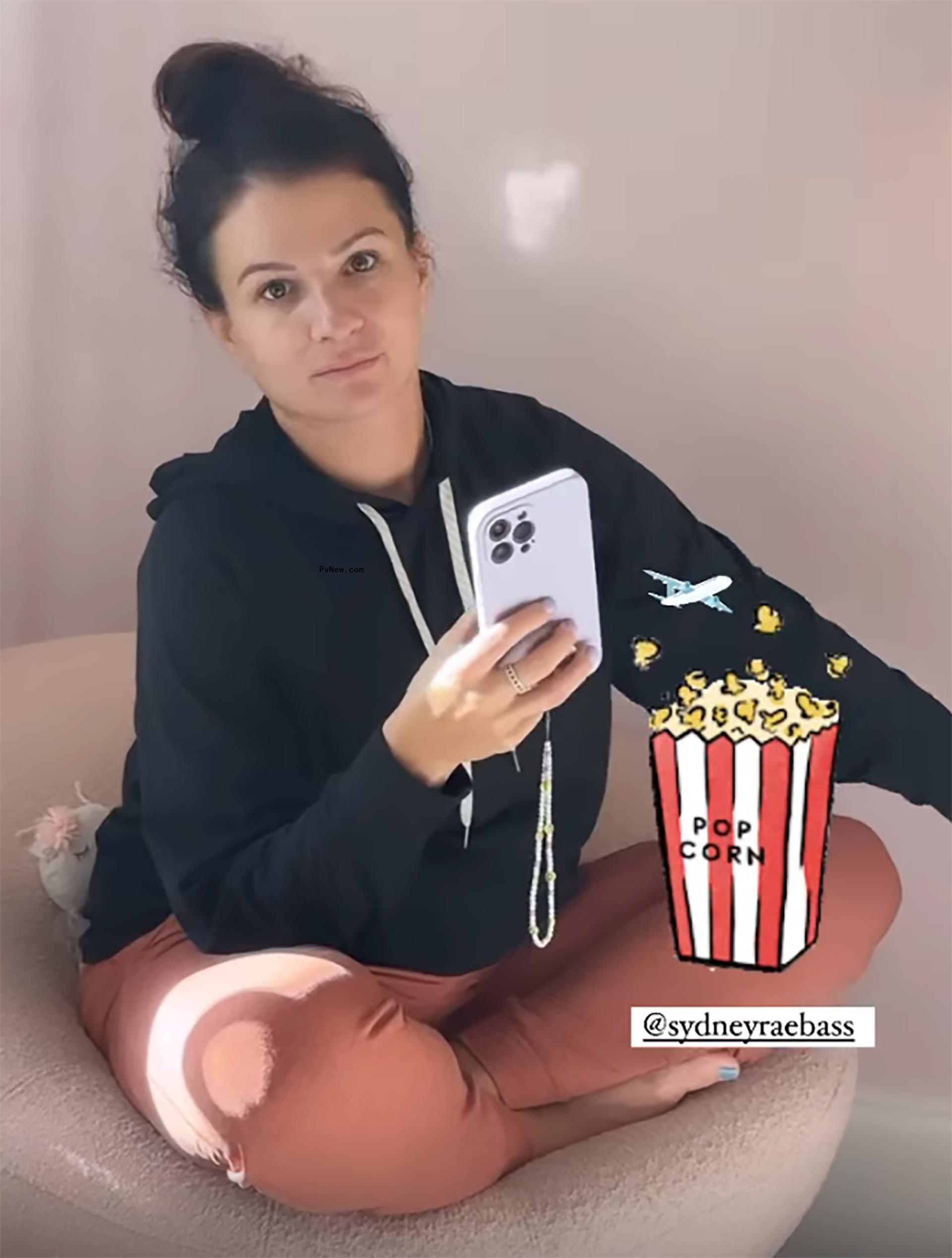 Sydney Rae Bass sitting, holding phone