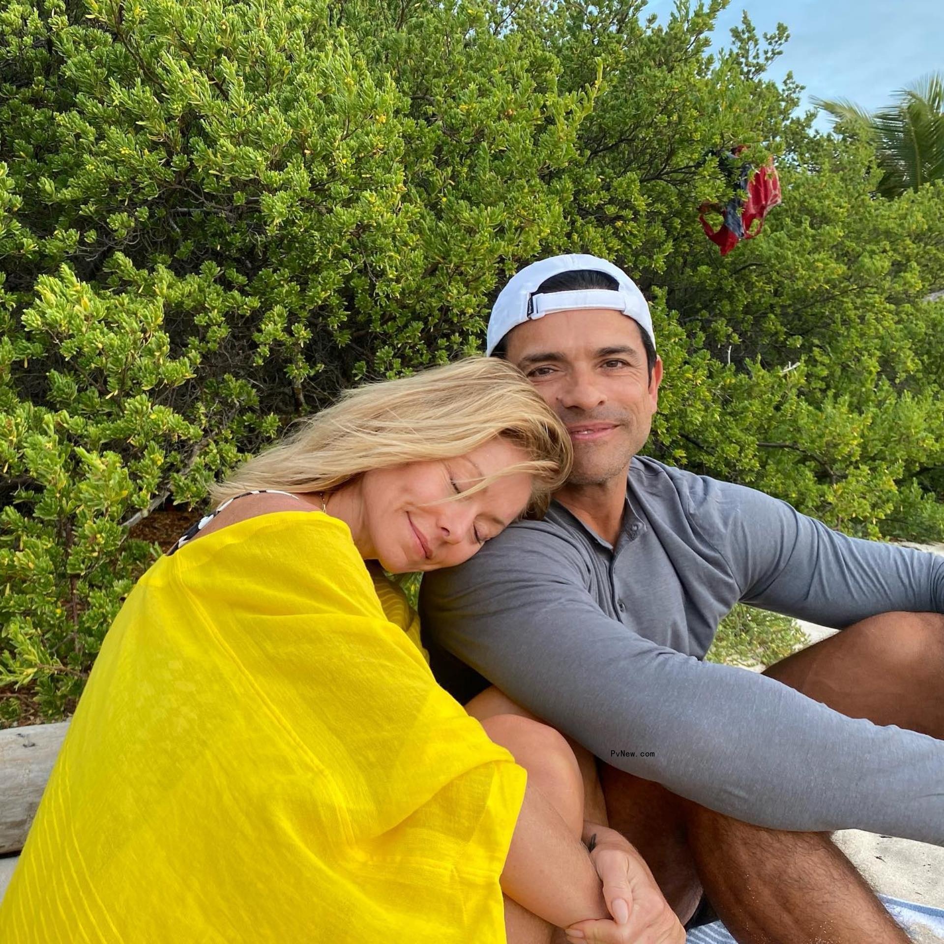 Kelly Ripa leaning on Mark Consuelos