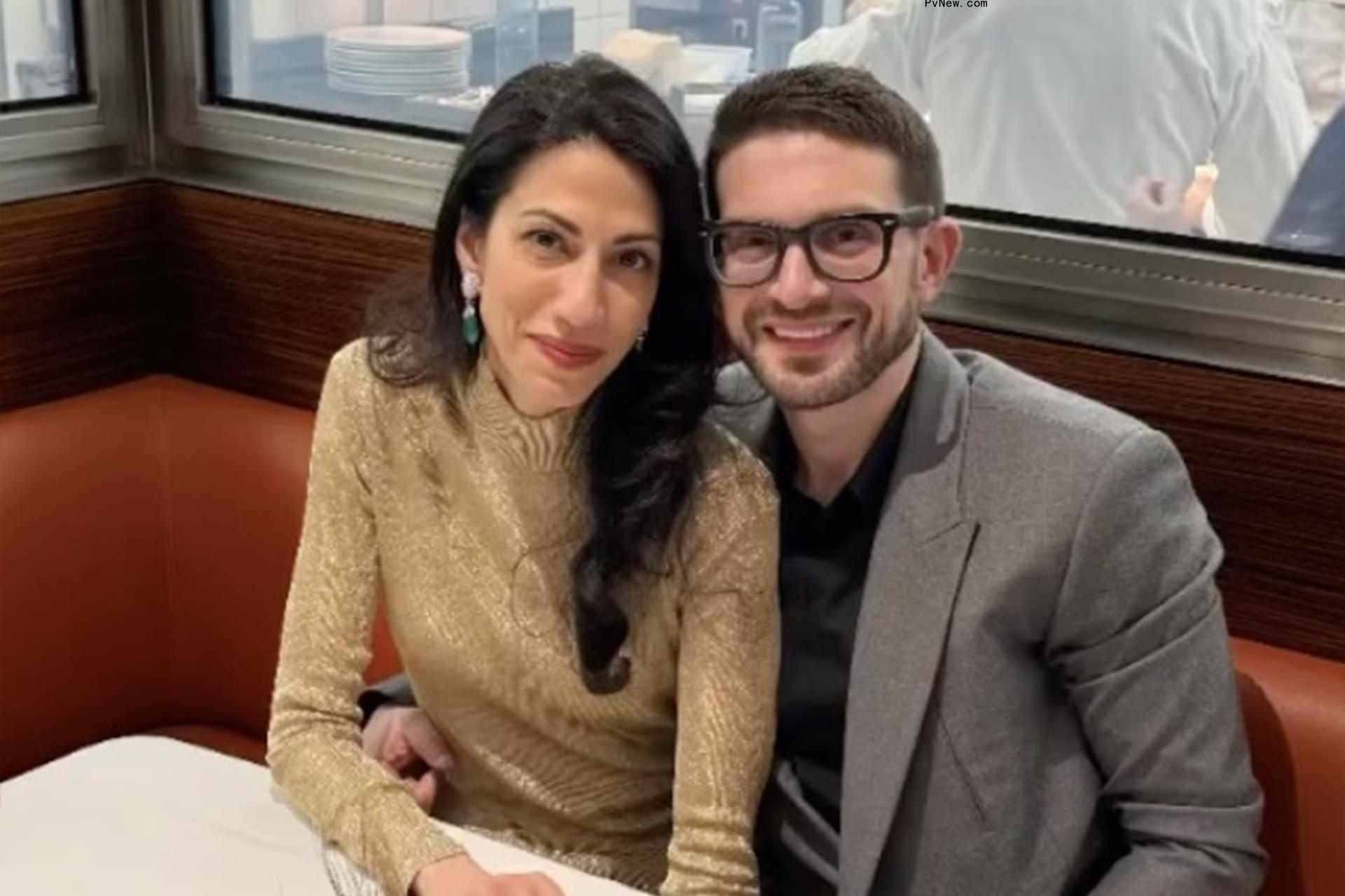 Alex Soros, seated, with his arm around Huma Abedin's waist