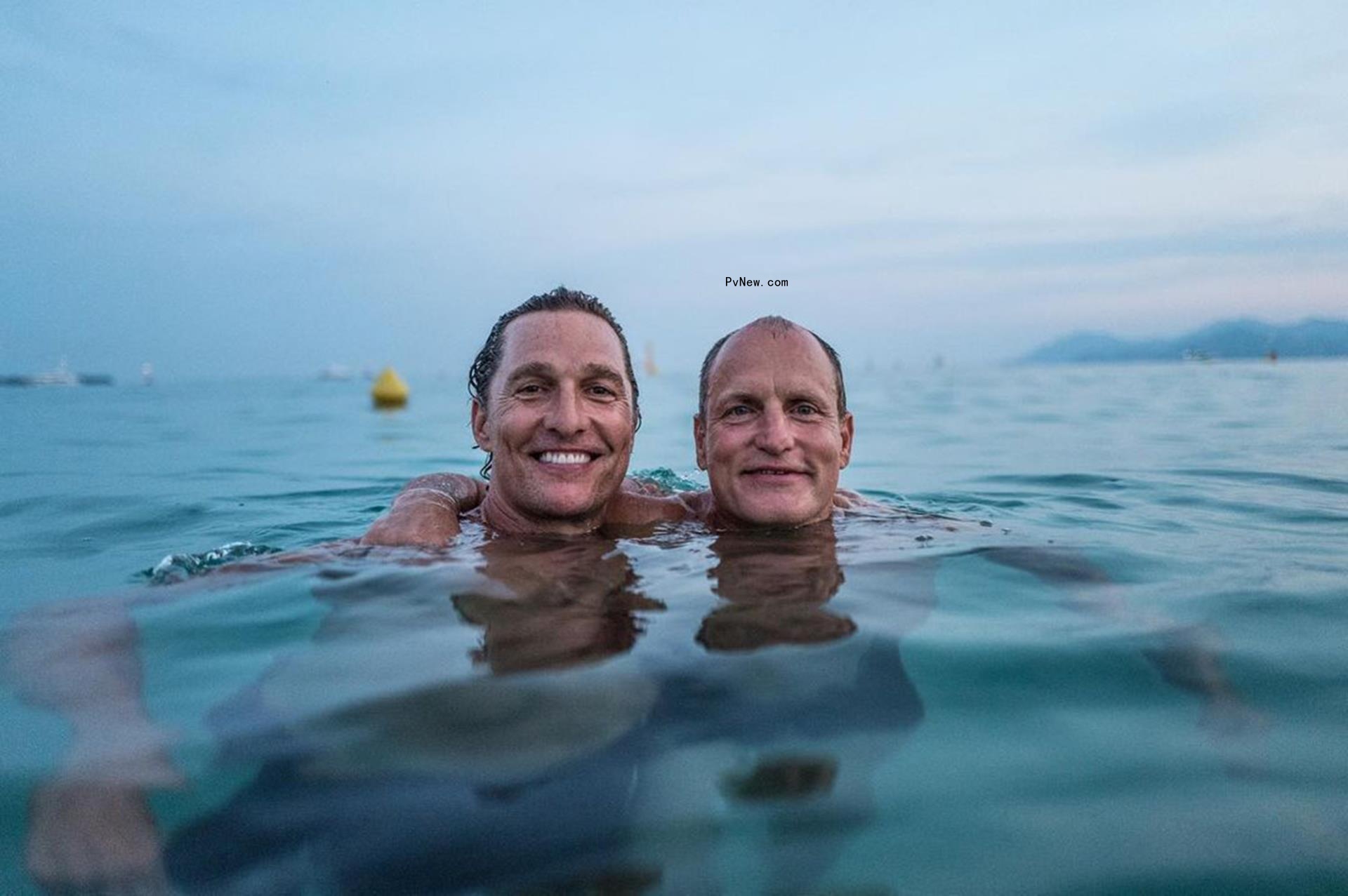 Woody Harrelson and Matthew McCo<i></i>naughey posing for a photo in a lake.
