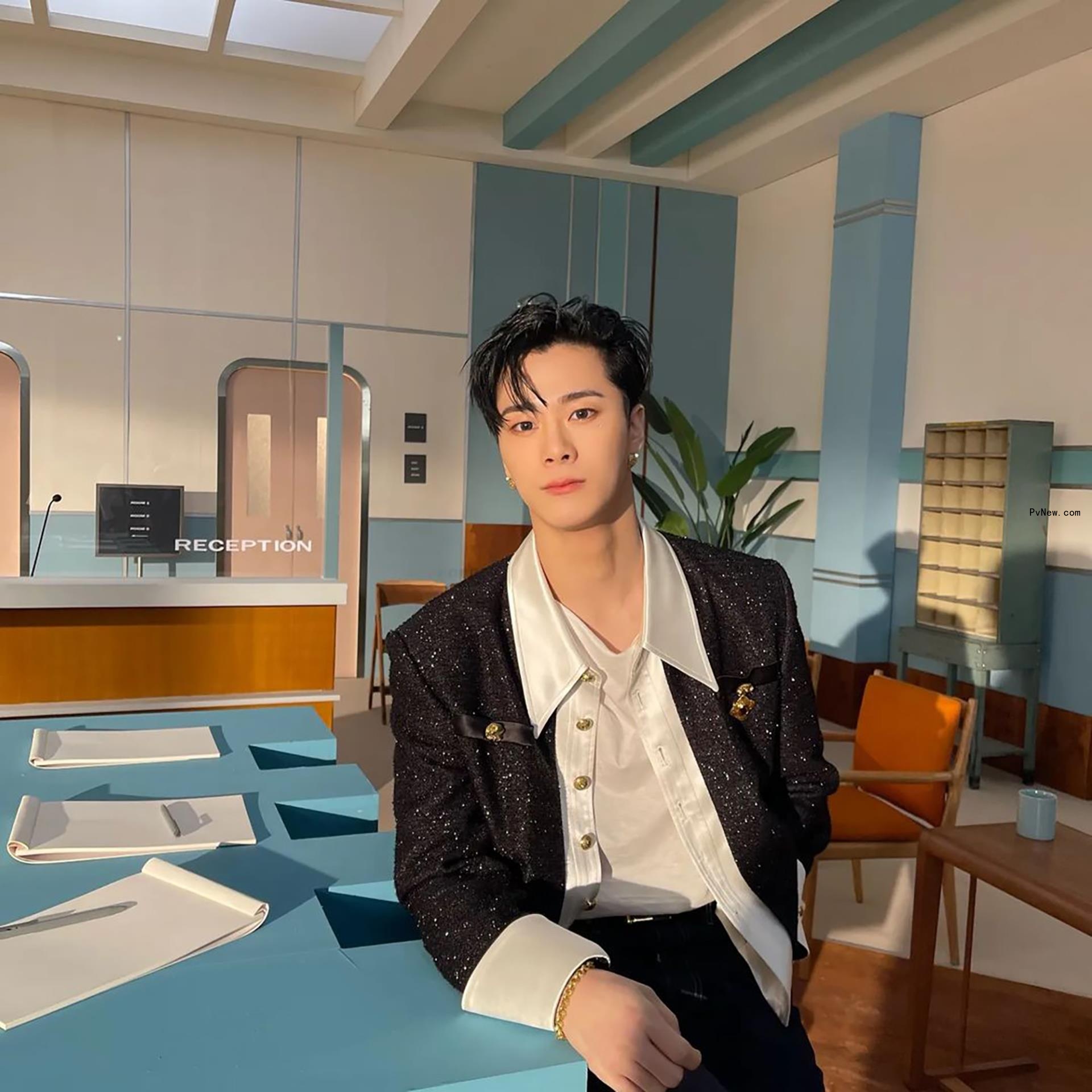 Moo<i></i>nbin sitting down while wearing a suit.