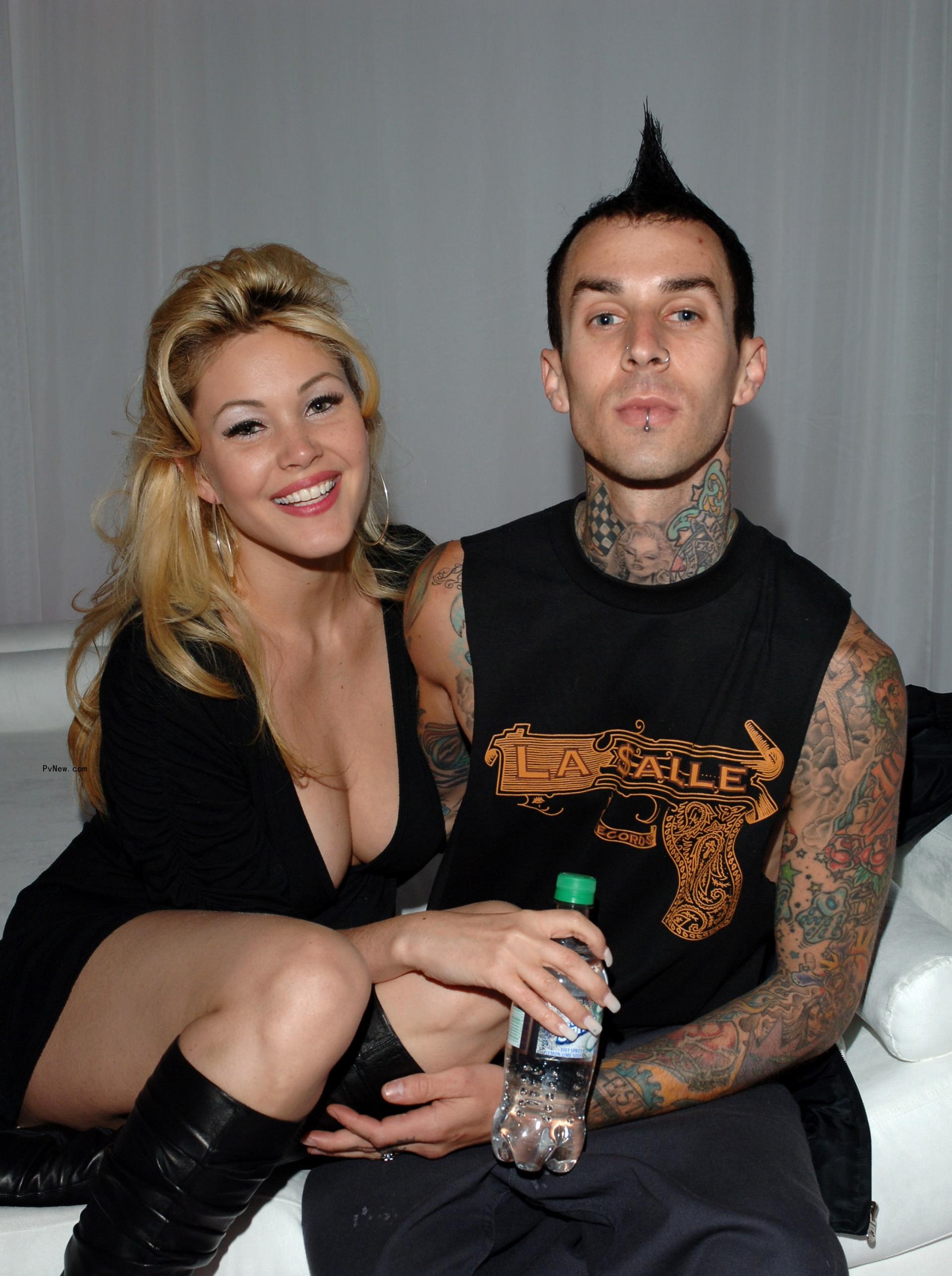 Kourtney Kardashian and Travis Barker sitting with their kids on a couch.