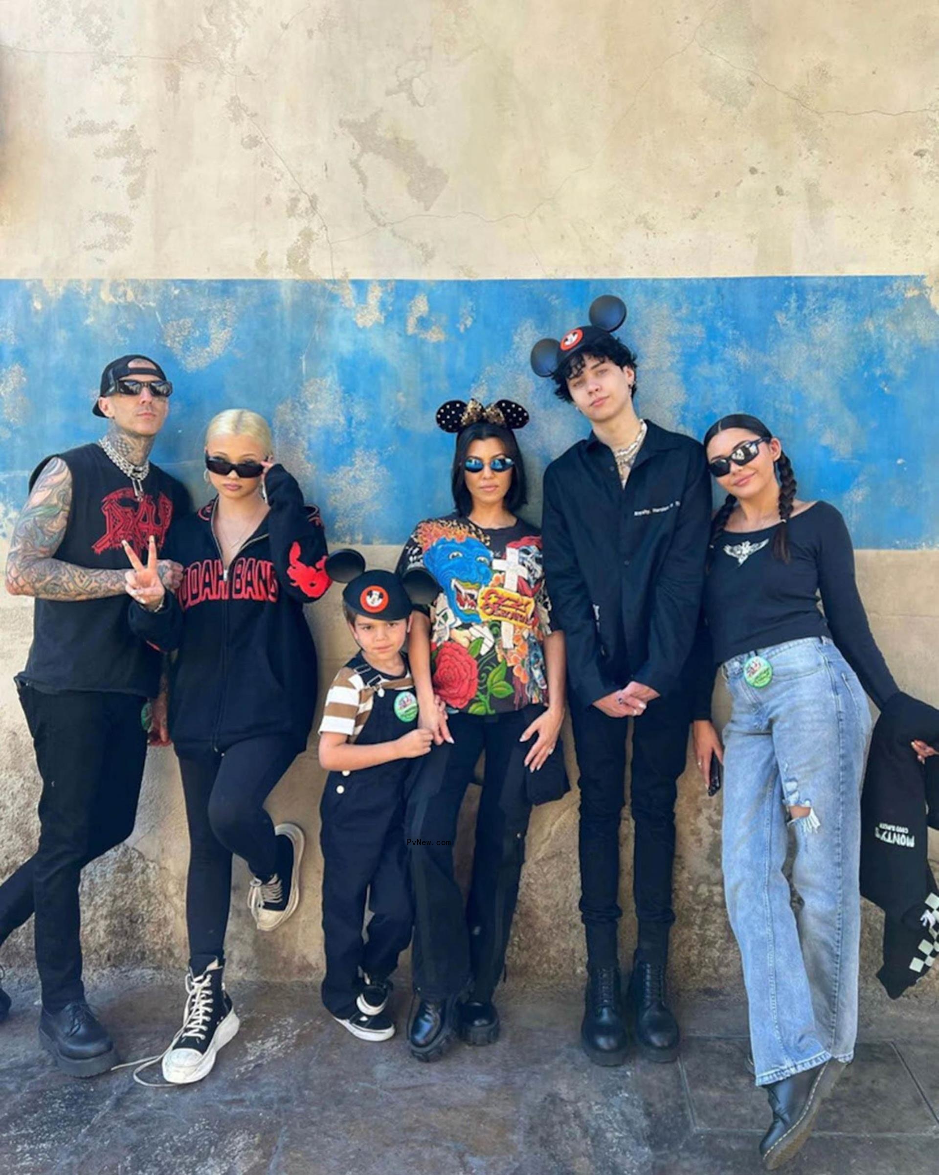 Kourtney Kardashian and Travis Barker posing with their kids at Disneyland.