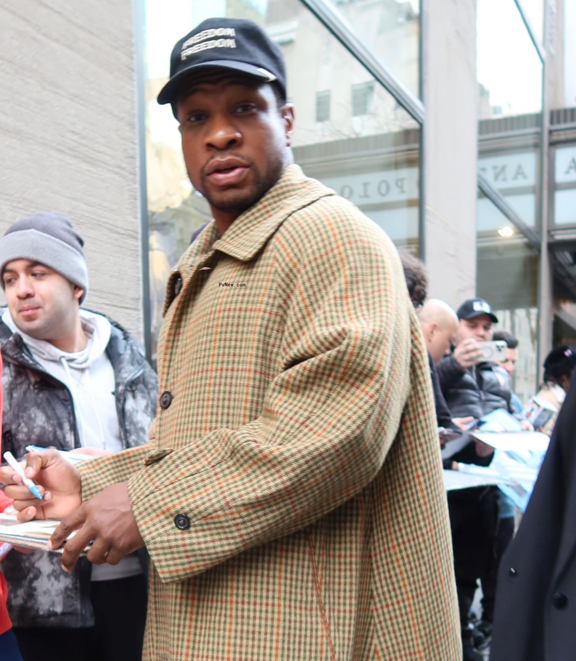 Jo<i></i>nathan Majors signing an autograph.