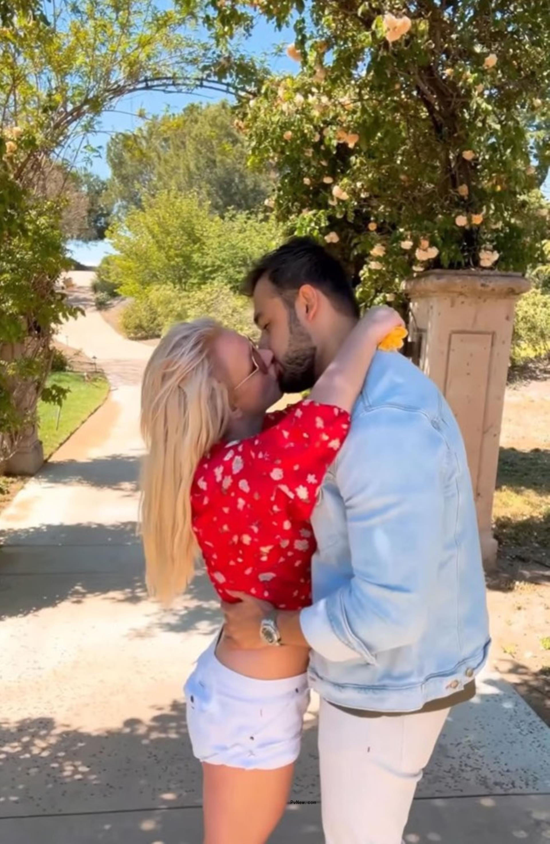 Britney Spears and Sam Asghari kissing outdoors.