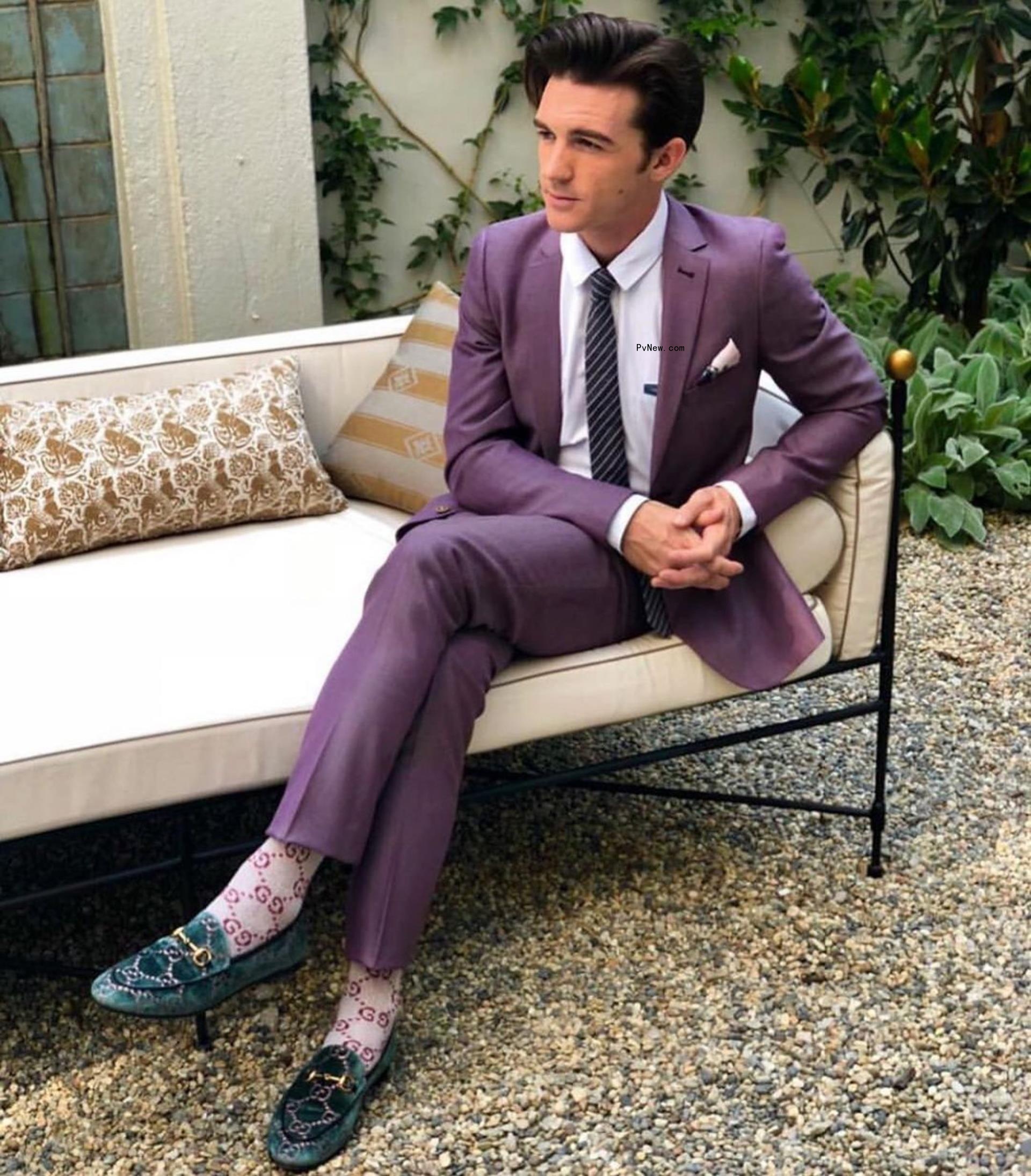 Drake Bell sits in purple suit