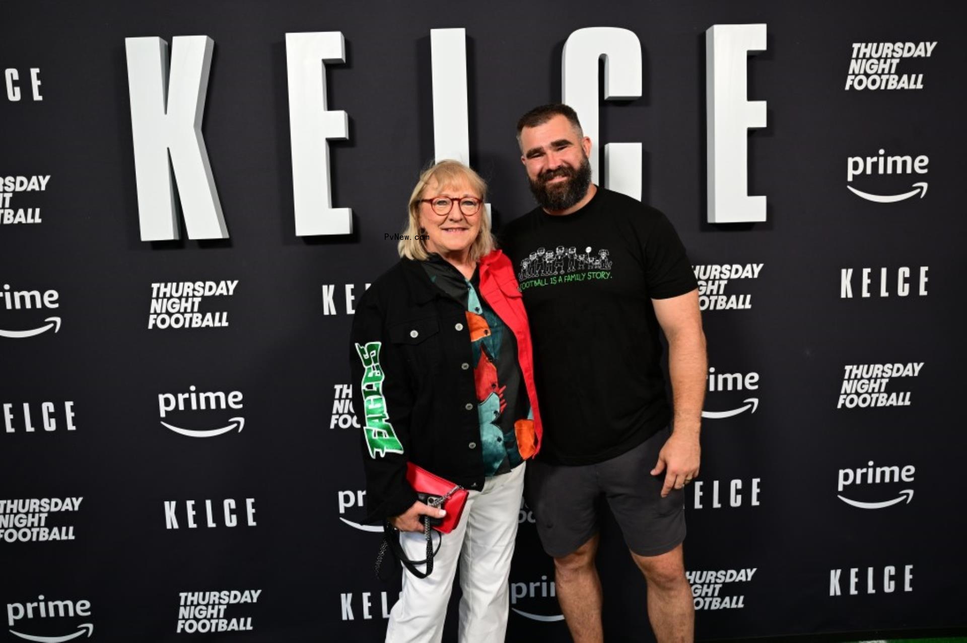 Do<i></i>nna Kelce and Jason Kelce stand next to one another in front of a black Kelce sign