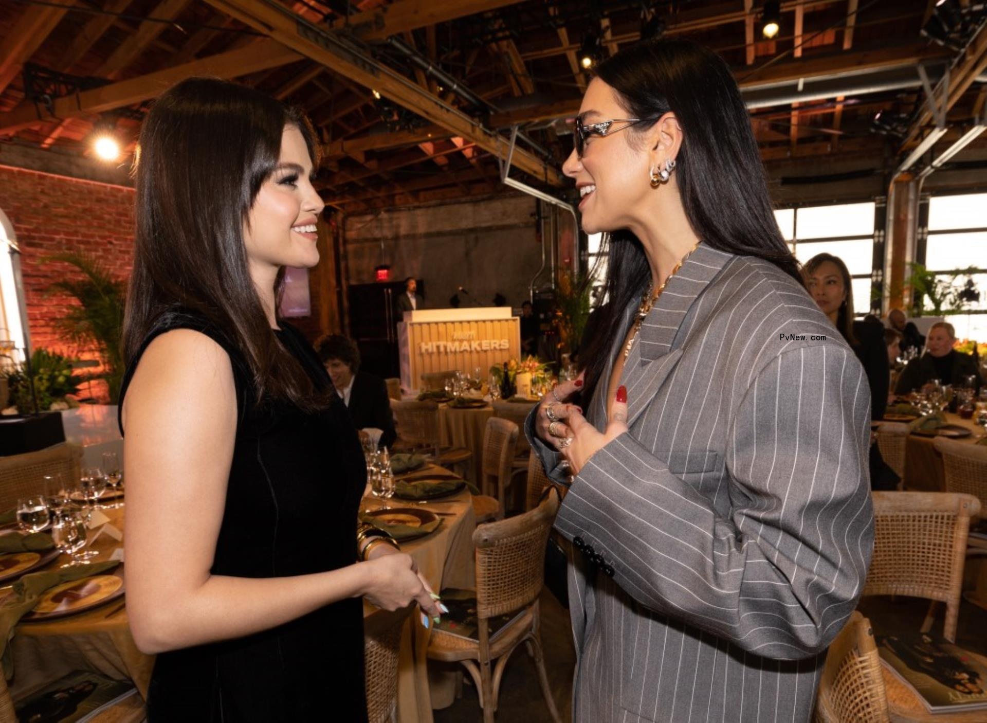 Selena Gomez and Dua Lipa chatting in formal wear.