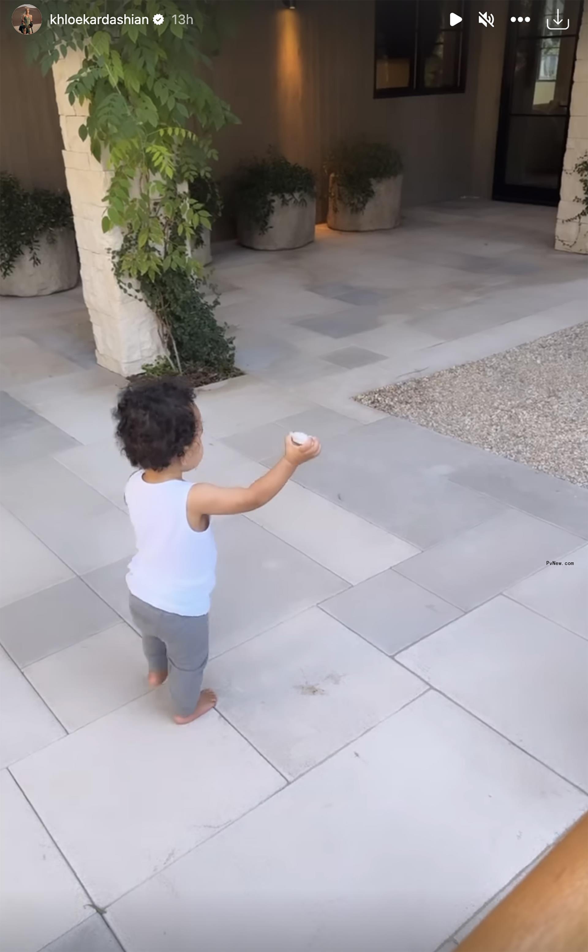 Tatum dressed in gray sweats and a white tank top walking on gray pavers.