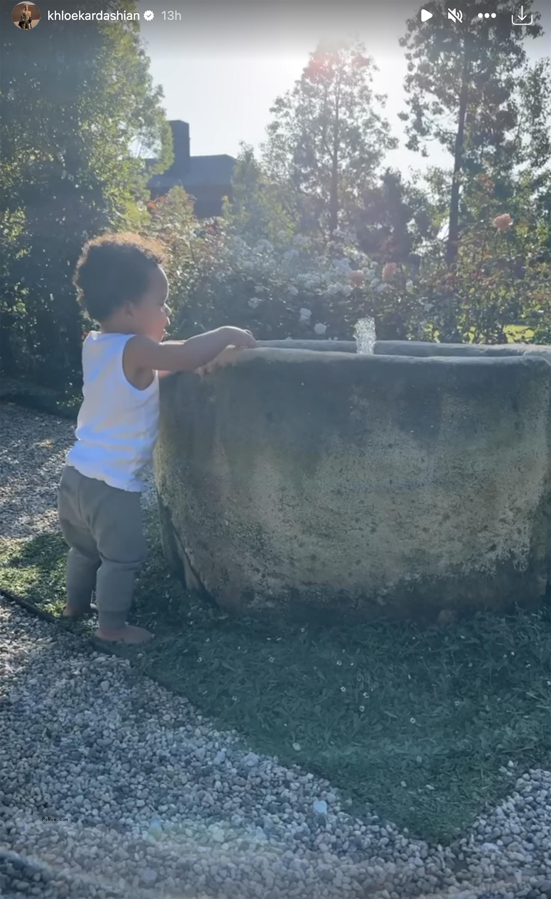 Tatum Thompson dressed in gray sweats and a white tank top playing in water fountain