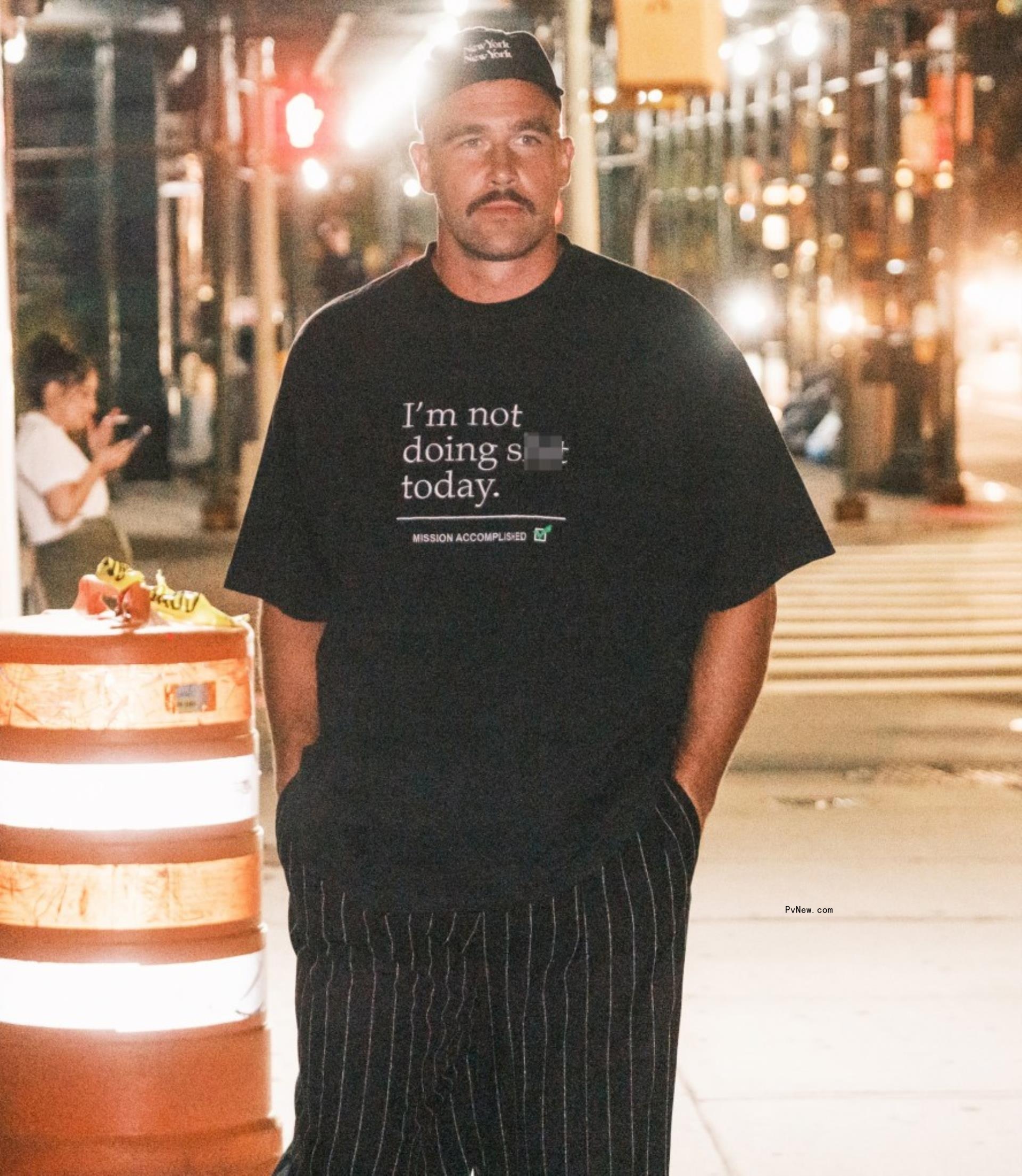 Travis Kelce walking on a city street in a black outfit 