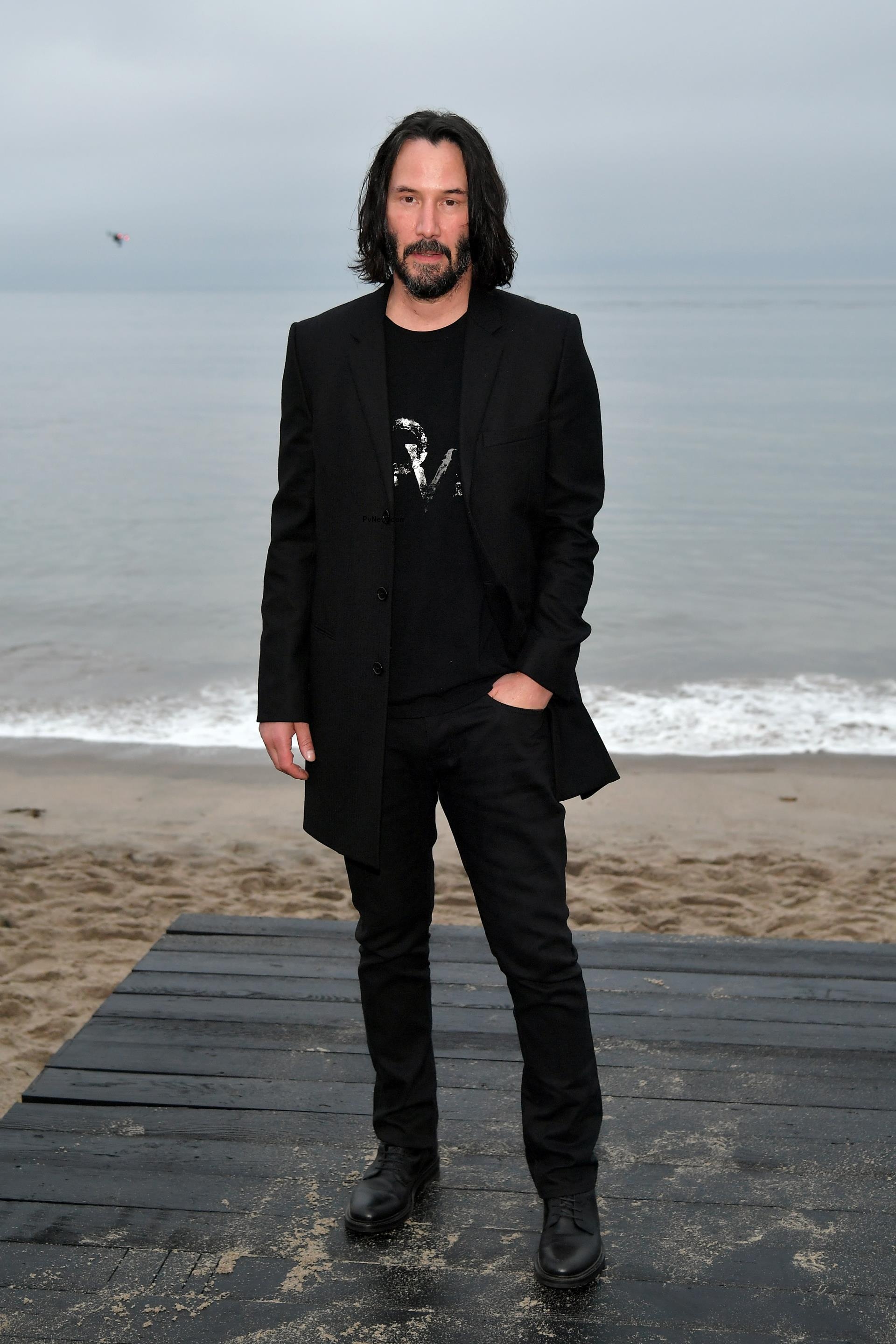 Keanu Reeves stands in suit