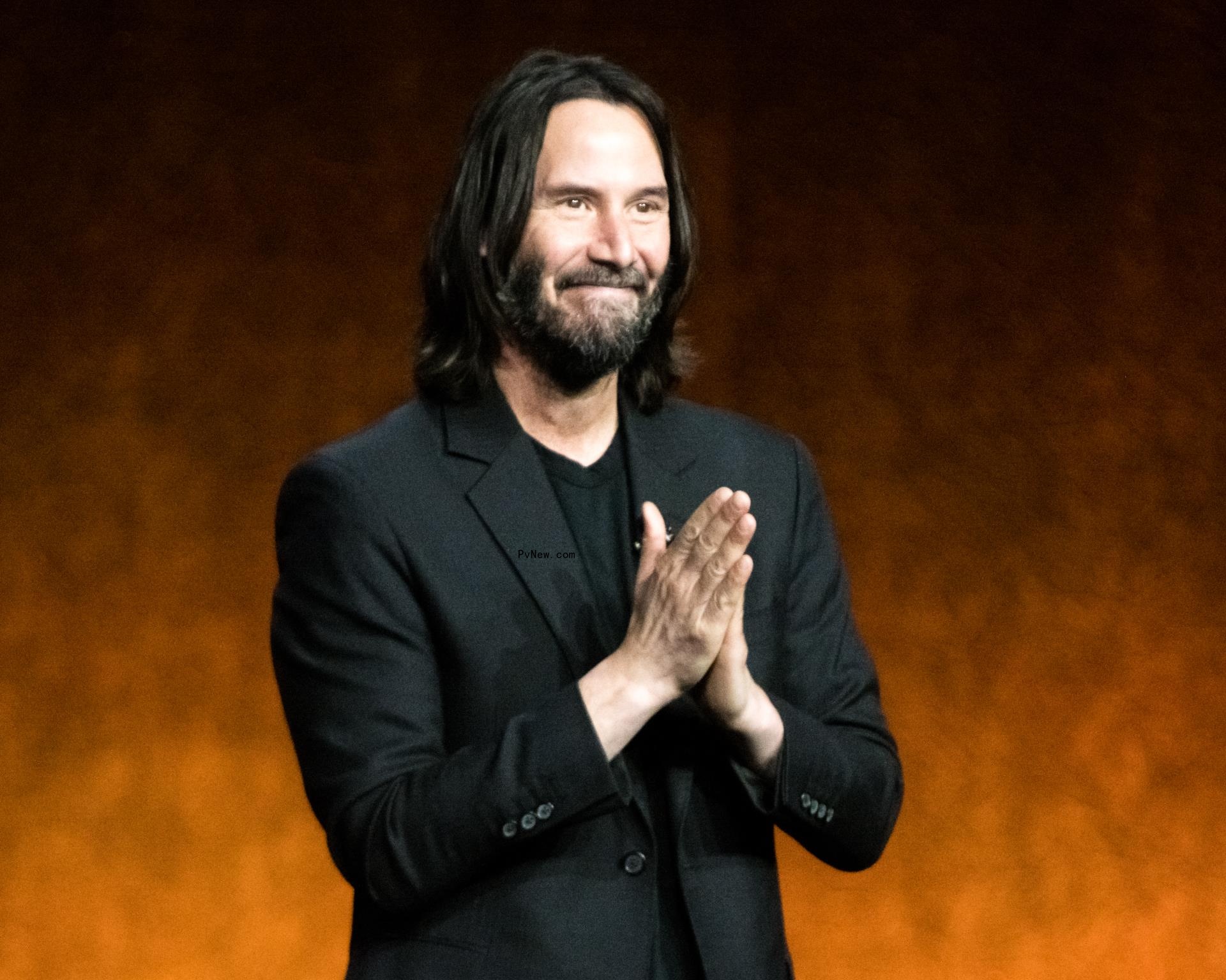 Keanu Reeves stands in suit