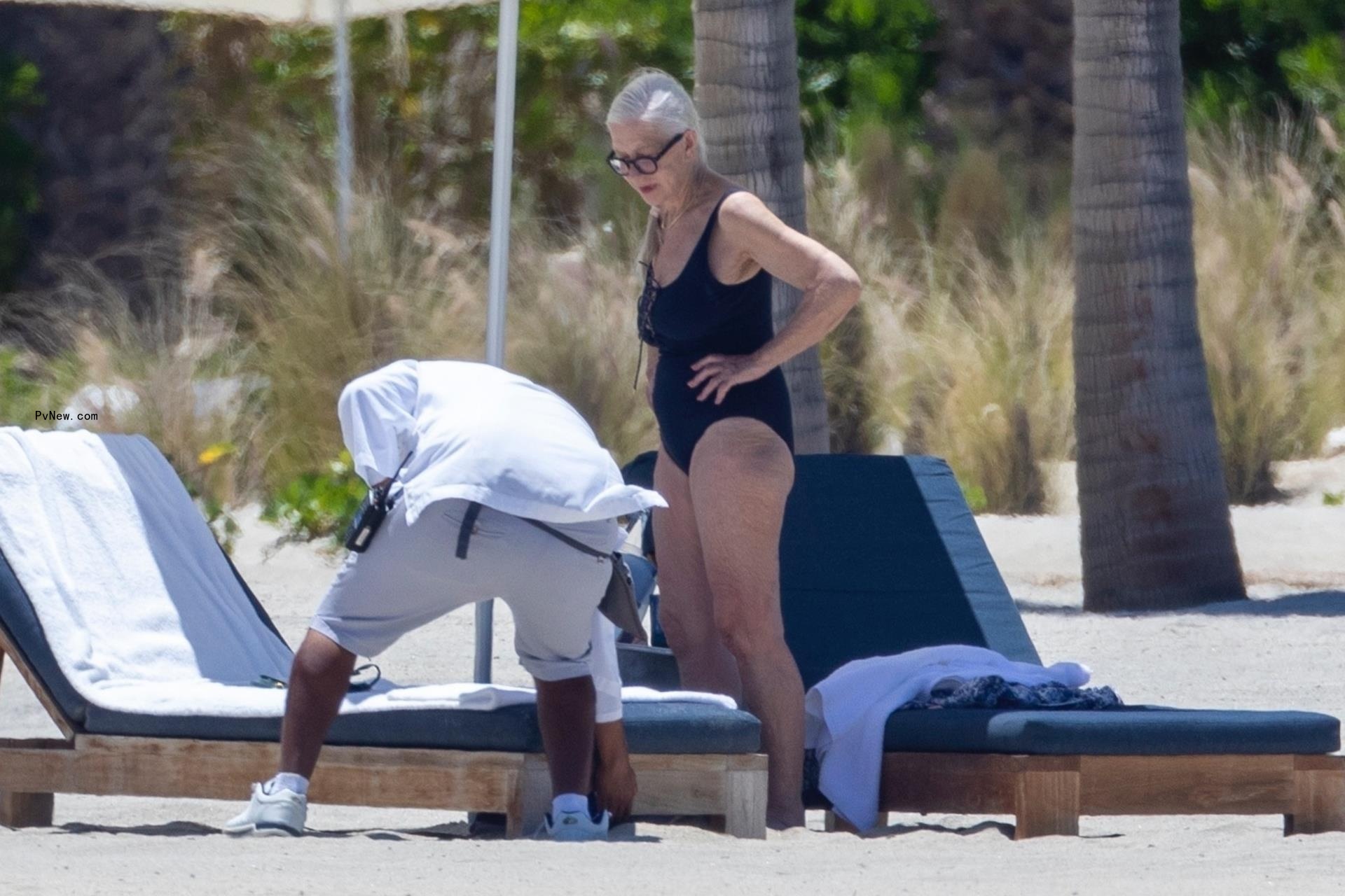Helen Mirren at the beach with an attendant helping her.