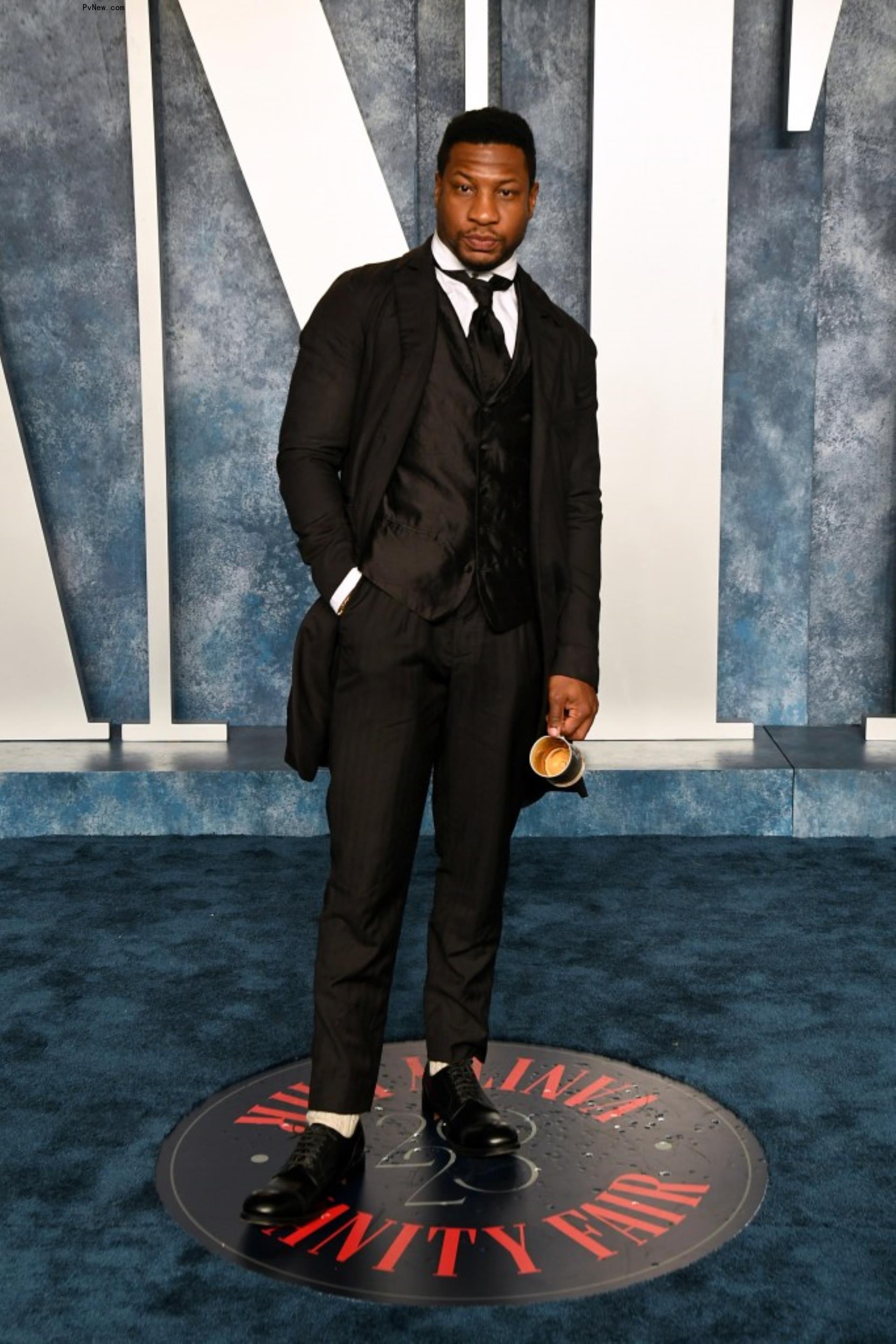 Jo<i></i>nathan Majors posing in tuxedo on the Vanity Fair red carpet.