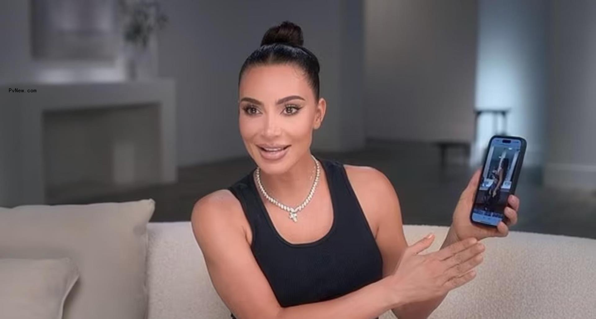 Kim Kardashian holding up her phone to show the mishap while speaking to cameras on 