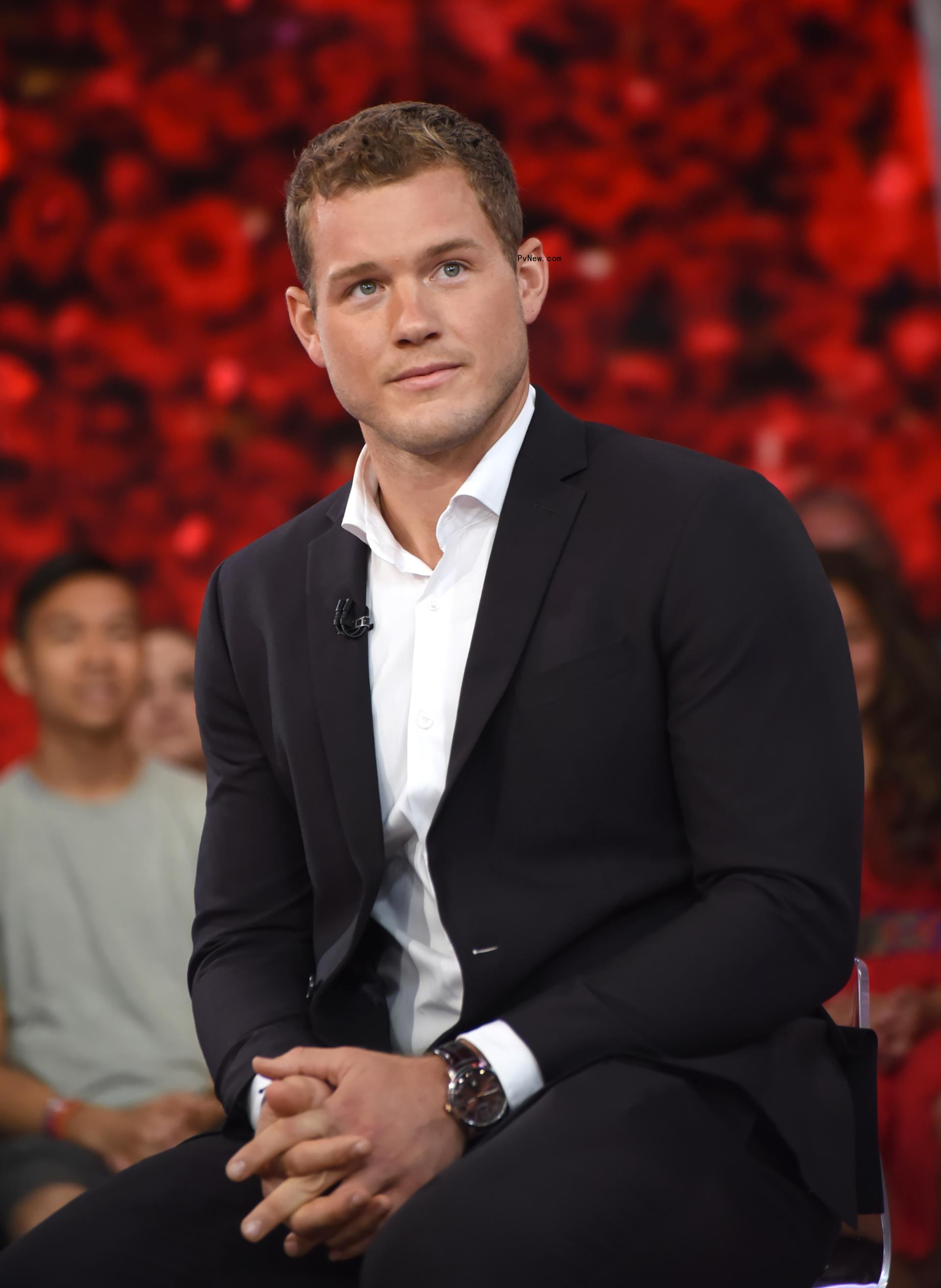 Colton Underwood sits in suit