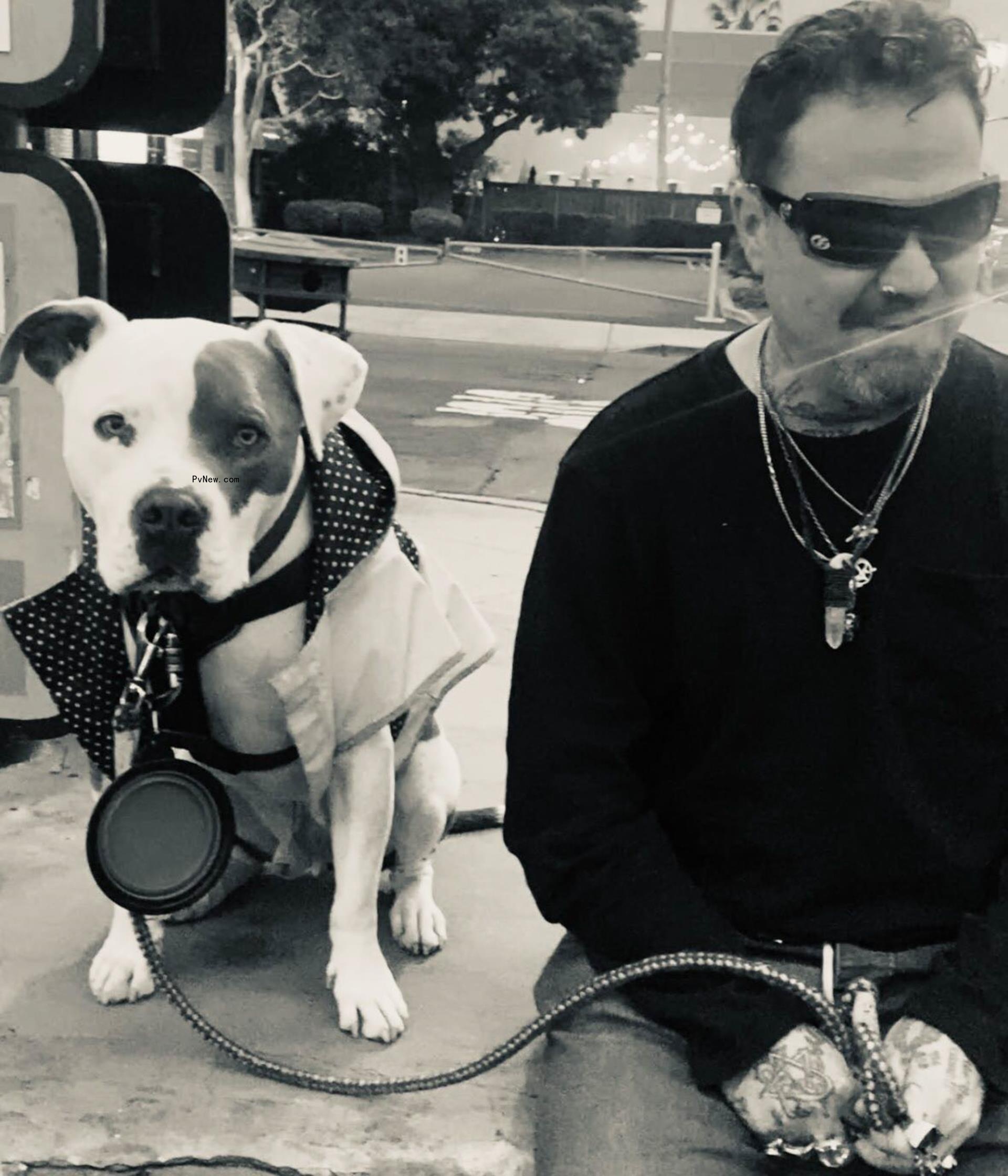 Bam Margera posing with a dog in a black-and-white-photo.