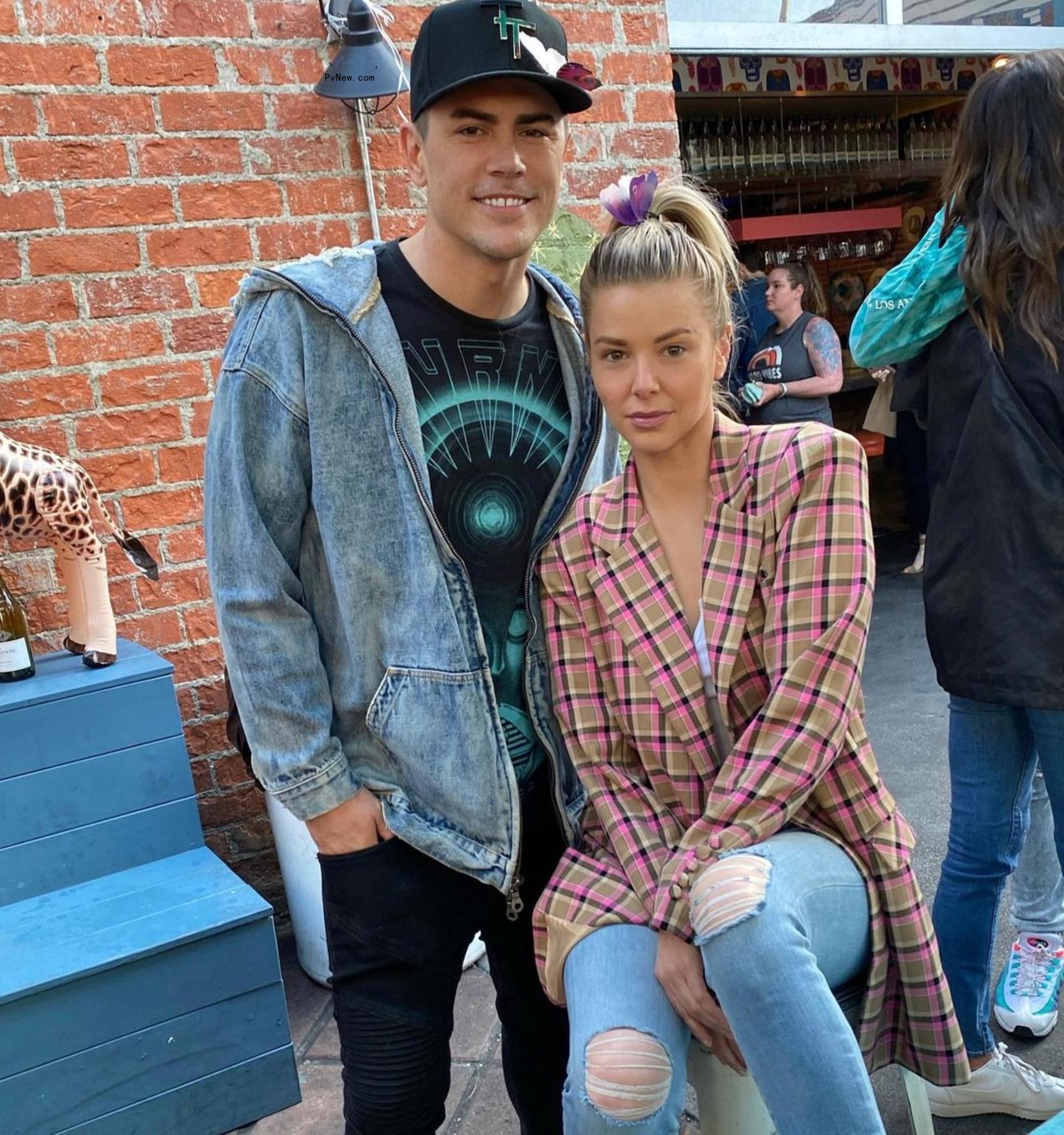 Ariana Madix sits beside standing Tom Sandoval