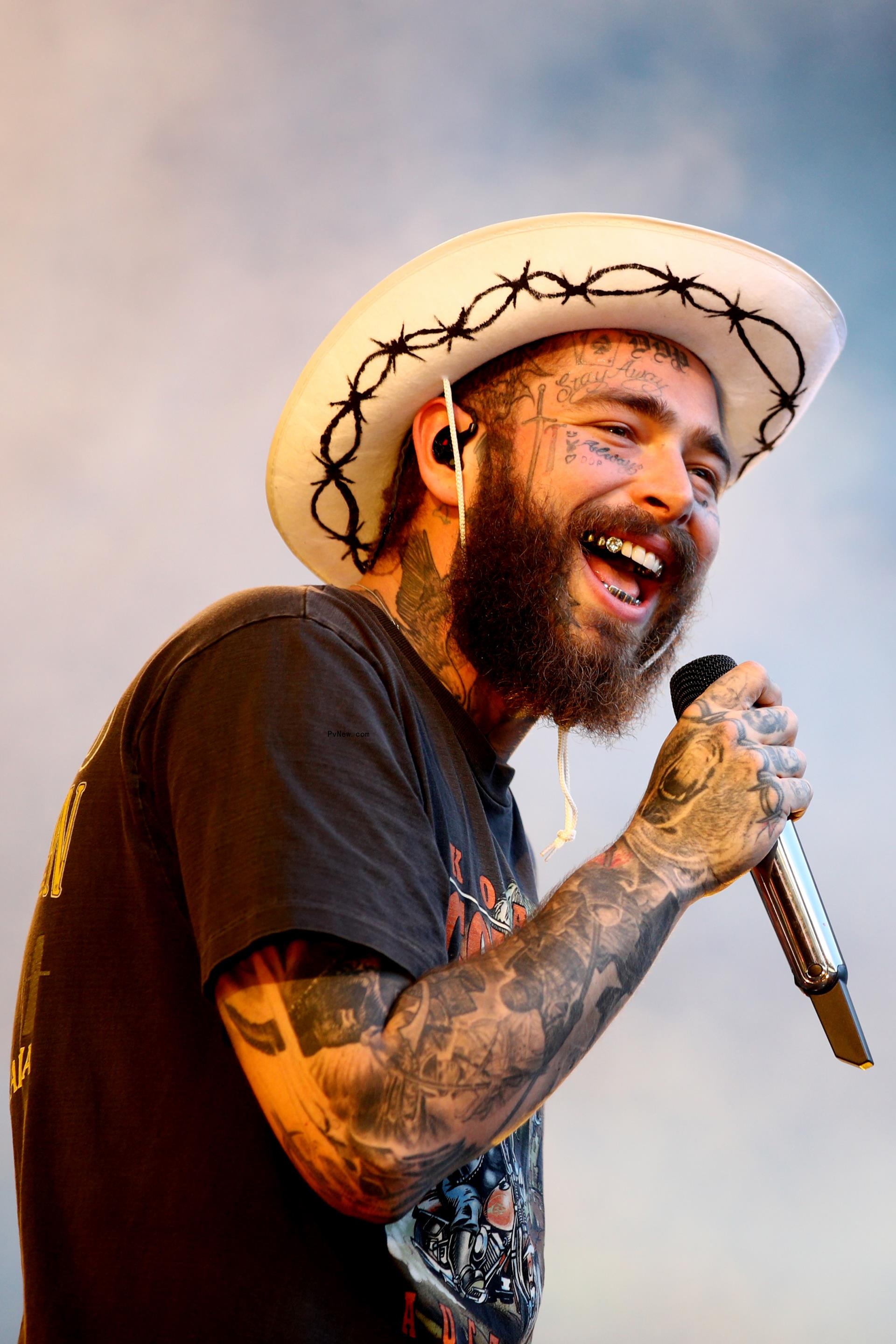 Post Malone singing and holding a mic while smiling.