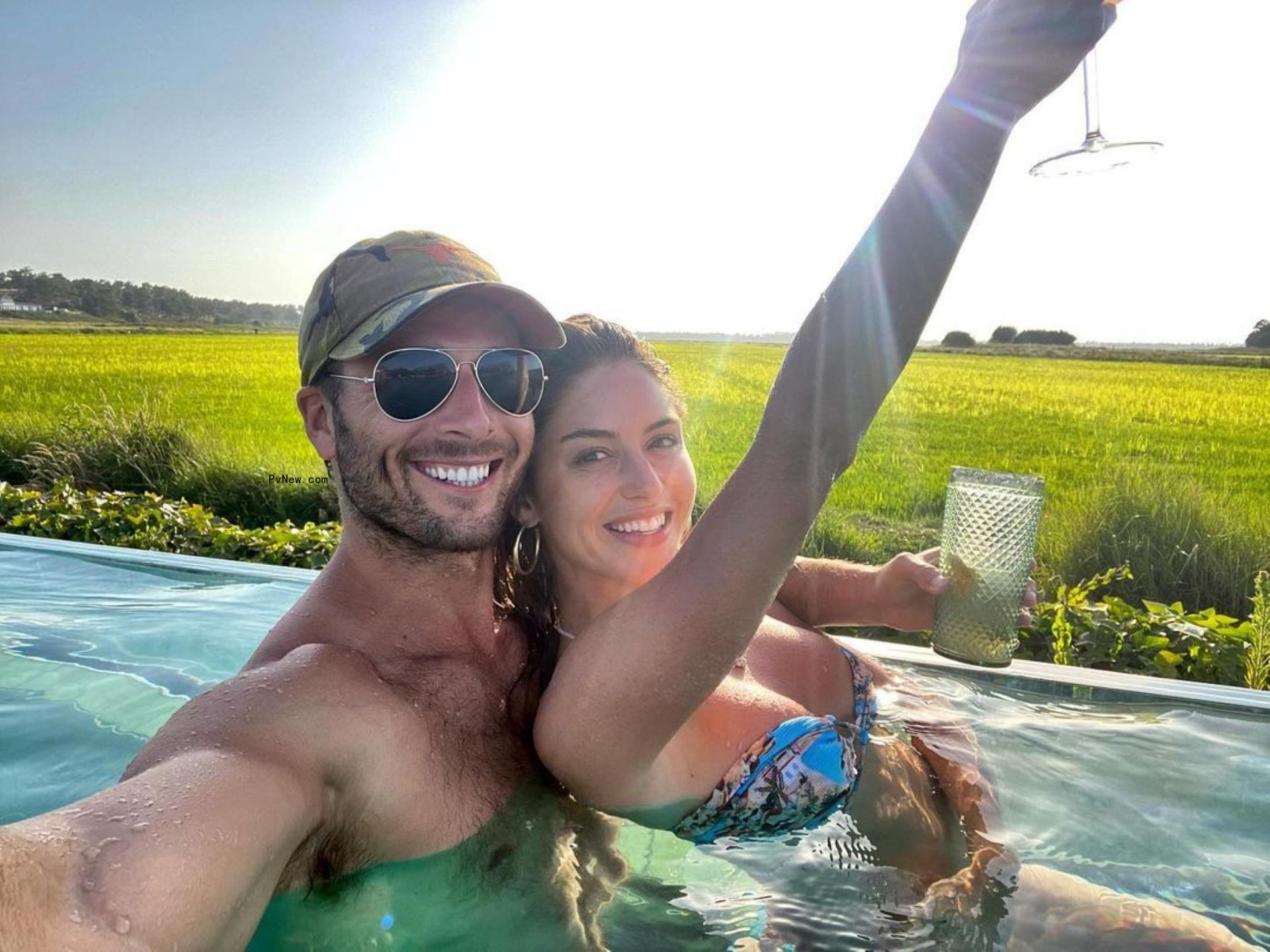 Gigi Paris and Glen Powell taking a picture together in a pool.