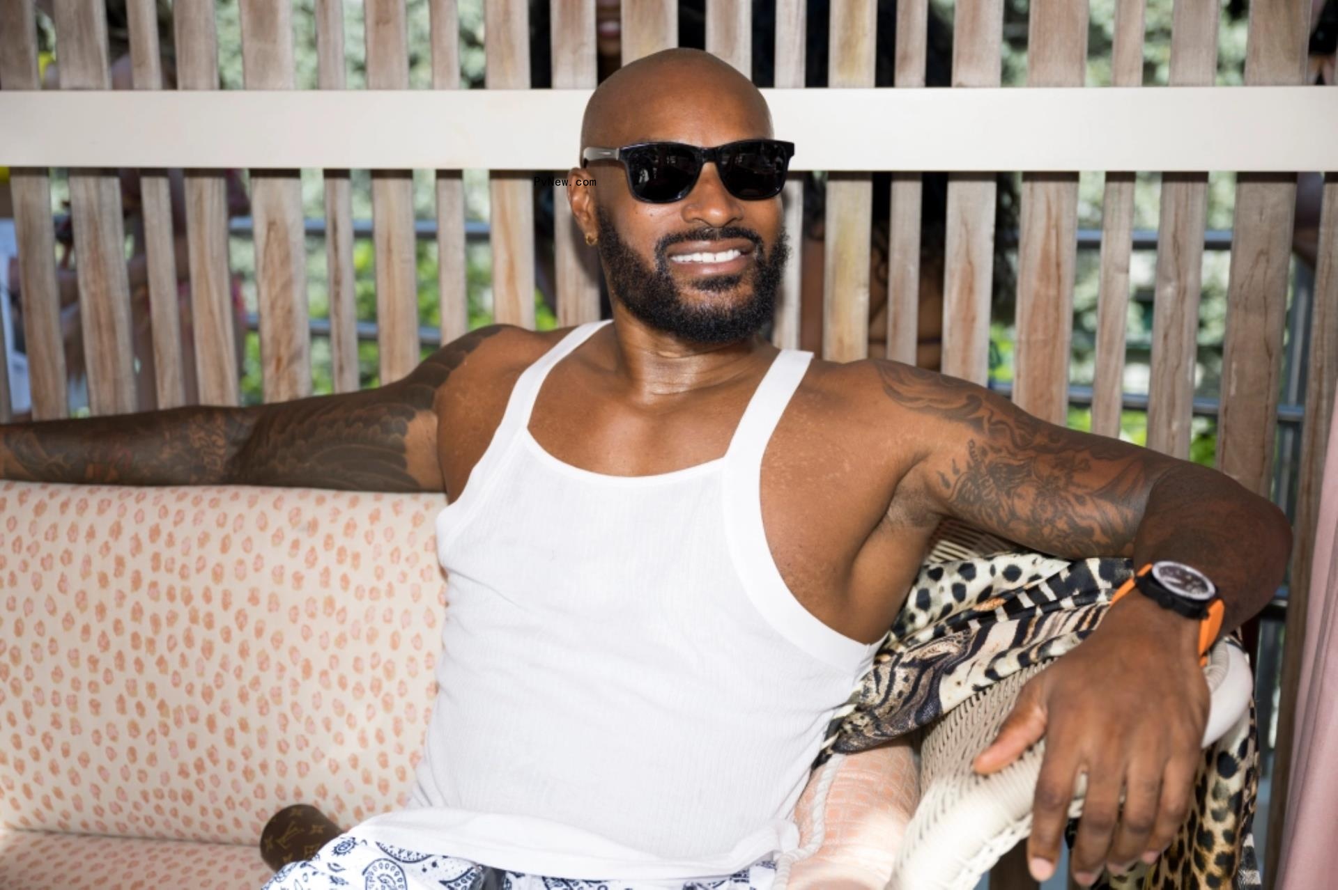 Tyson Beckford sitting on couch with black shades.