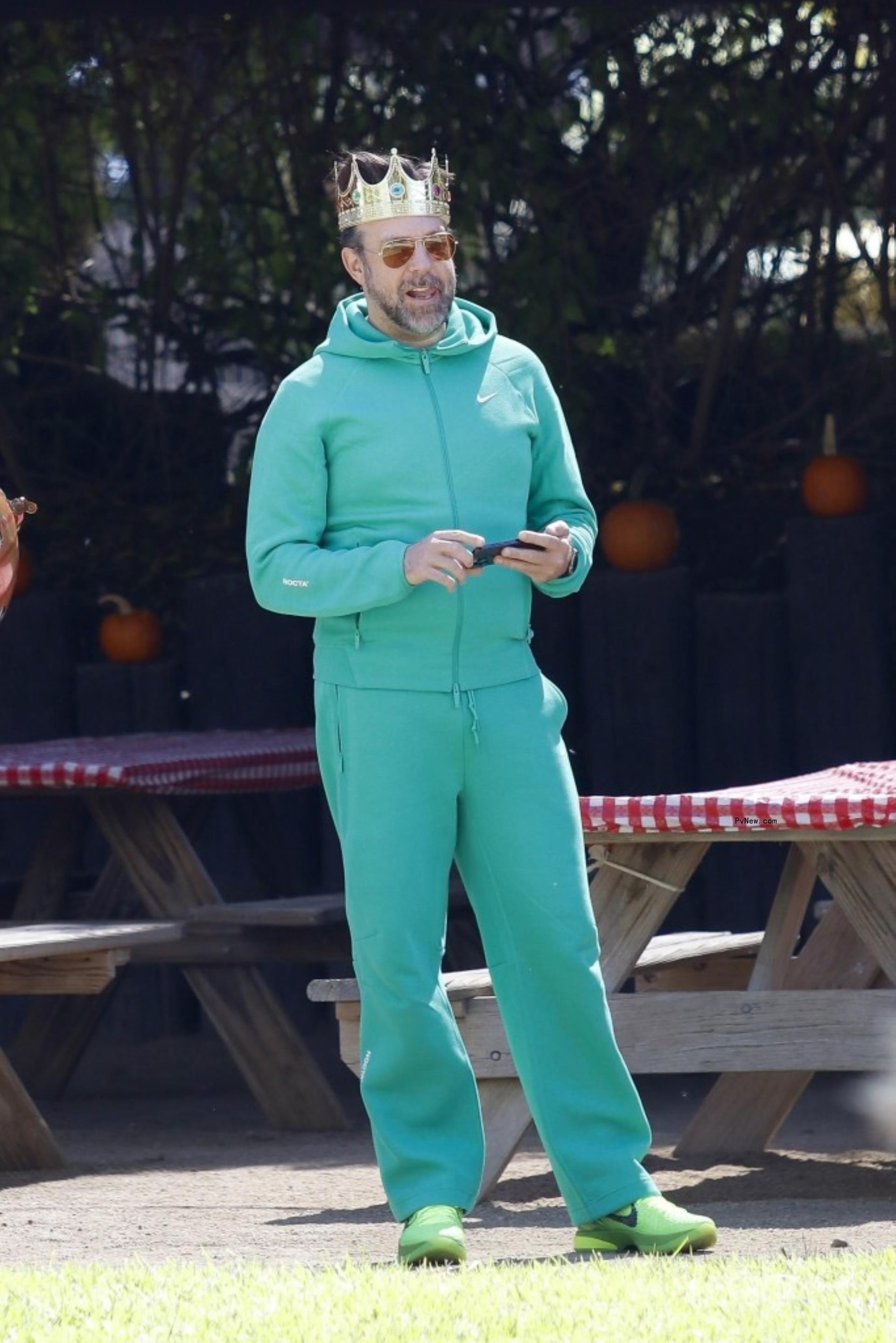 Jason Sudeikis in mint green sweats and zip-up plus a gold crown to look like The Statue of Liberty