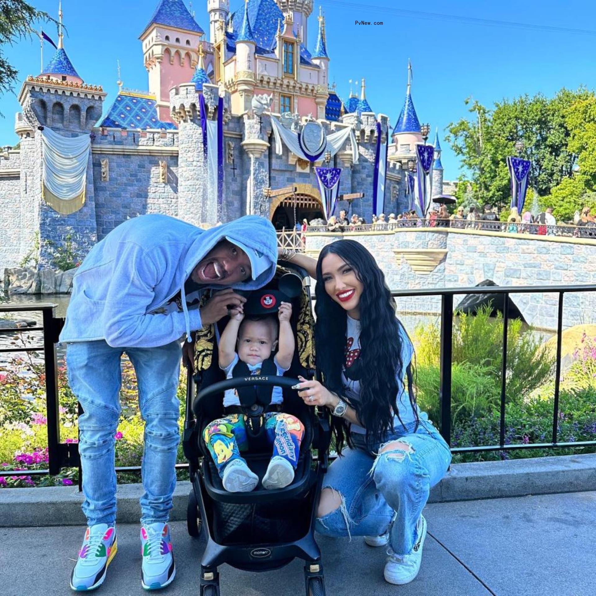 Nick Cannon and Bre Tiesi smile with their child at Disneyland in front of the castle