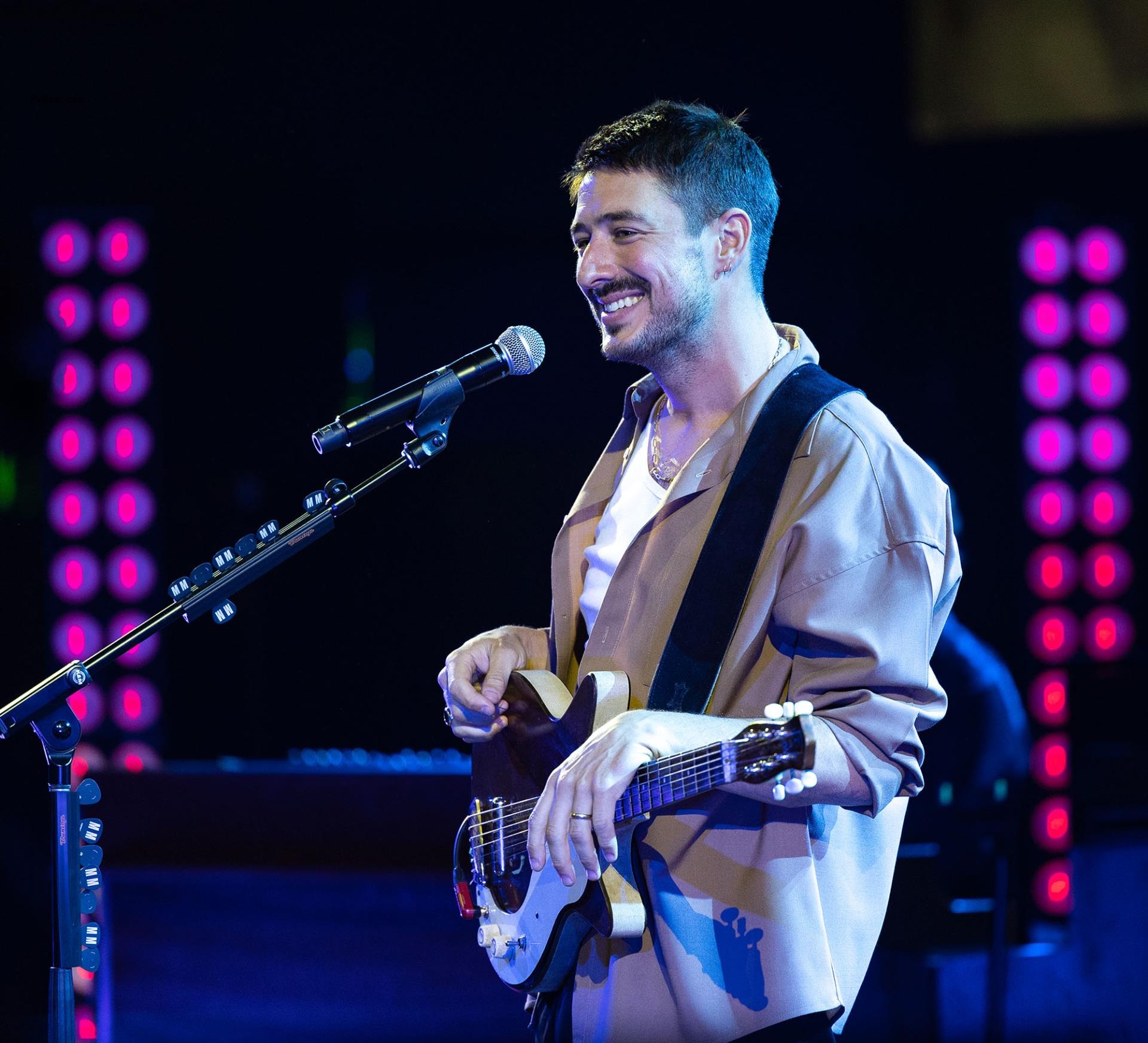 Marcus Mumford performing o<i></i>nstage with a guitar.