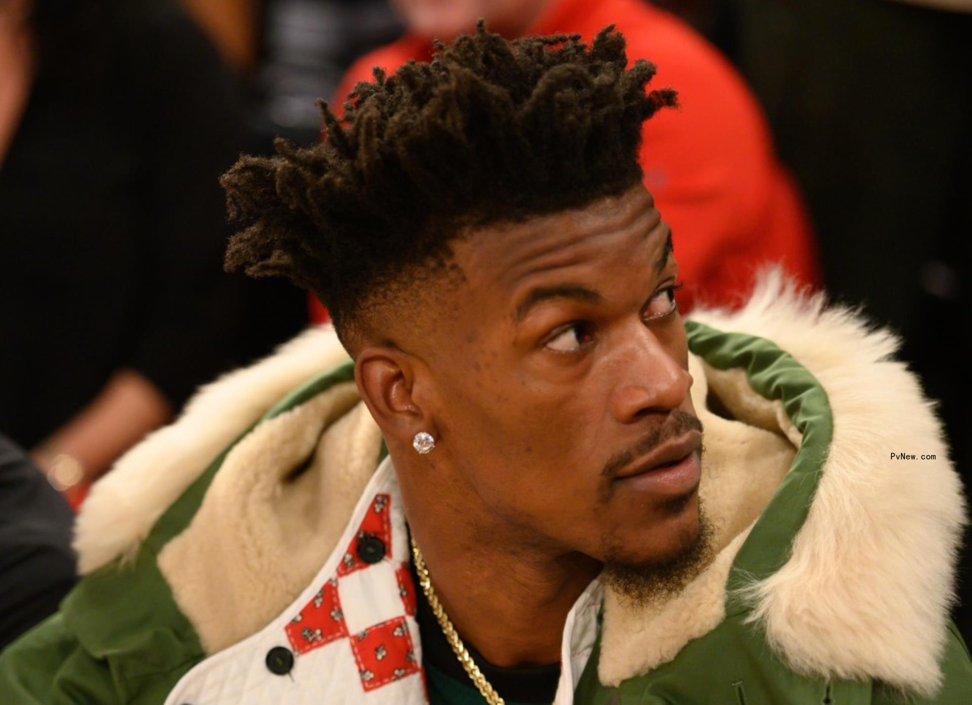 Jimmy Butler out of uniform sitting front row at NBA game.