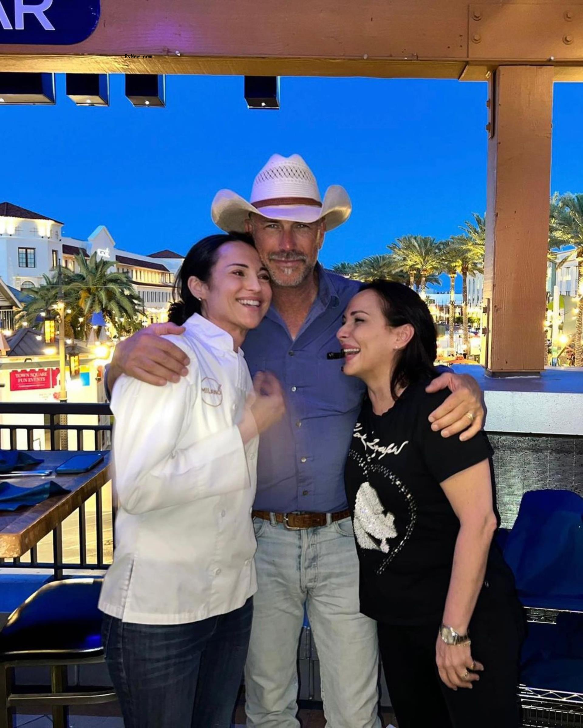 Kevin Costner posing for a photo with two women